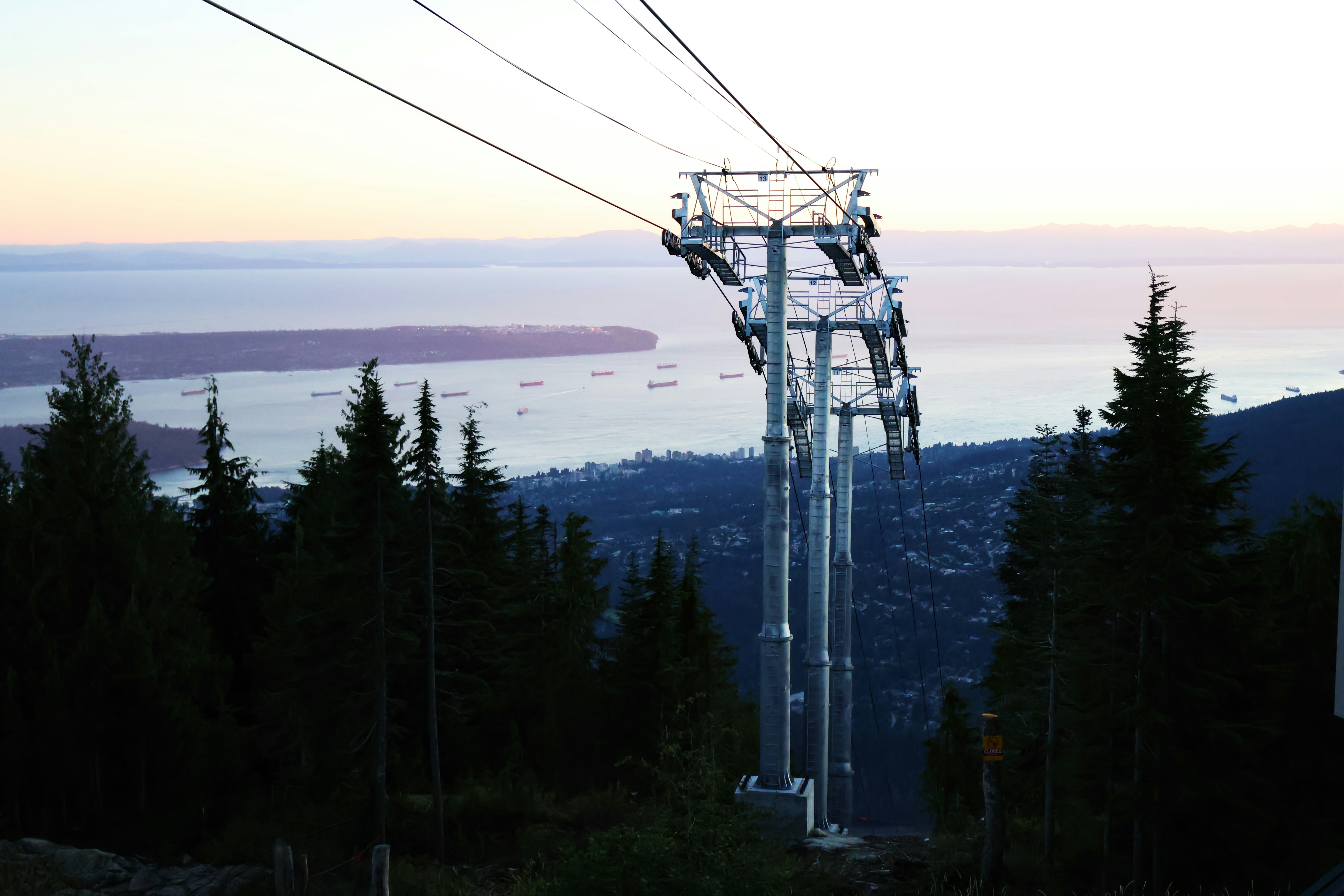 A ski lift going up a hill with a view of the ocean