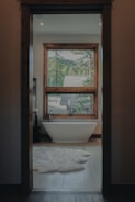 A bath room with a tub a window and a rug