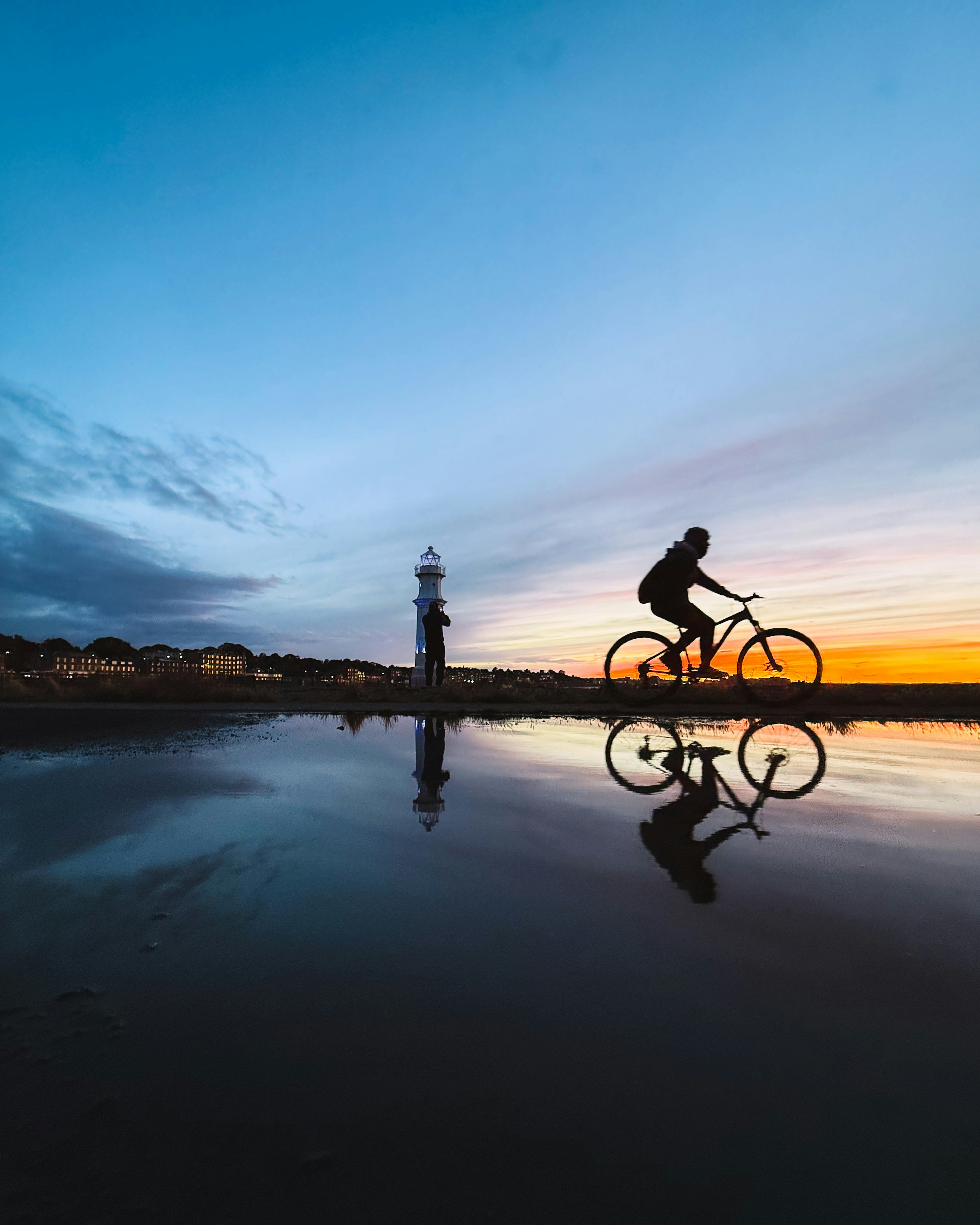 A person riding a bike on a beach at sunset