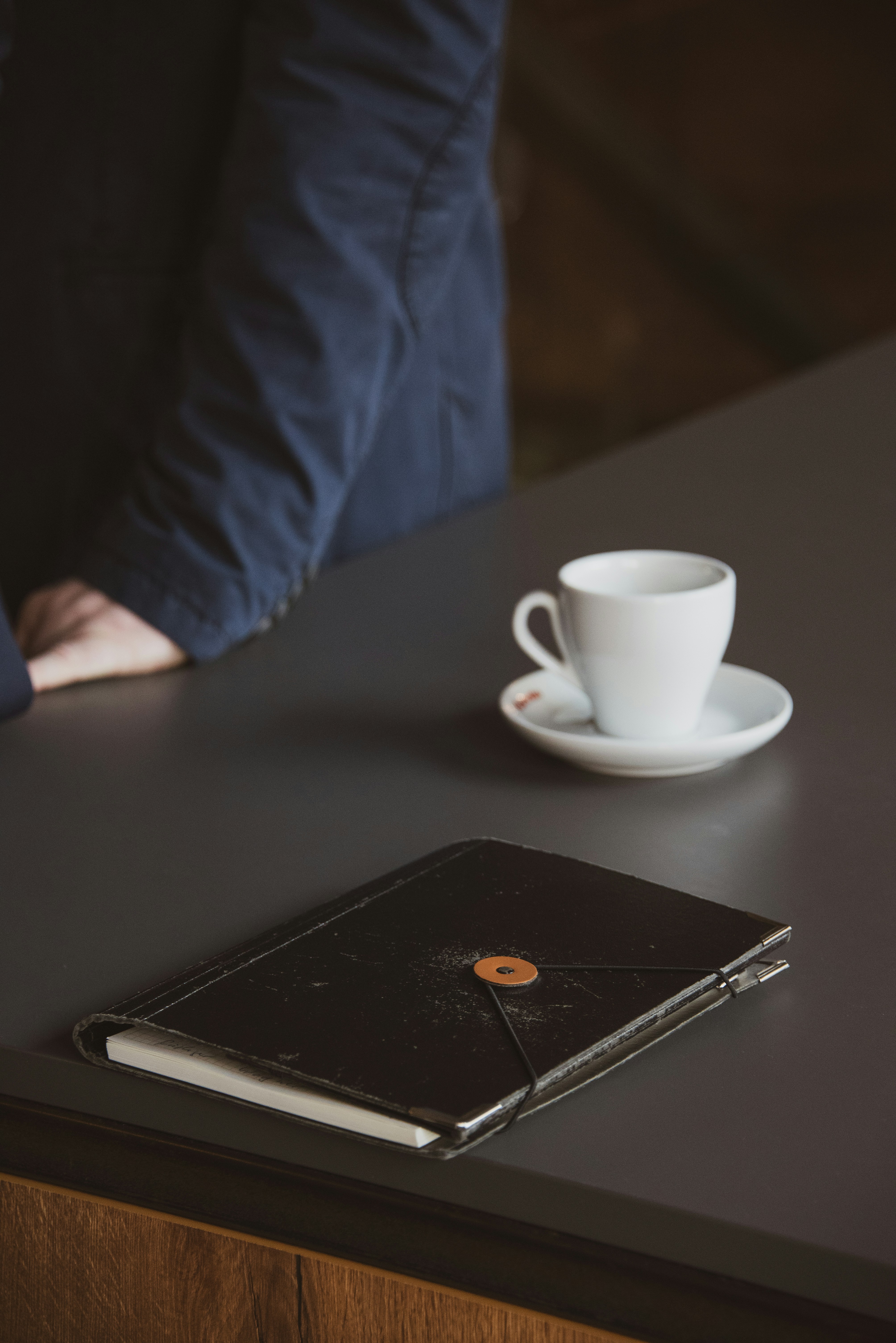A person sitting at a table with a book and a cup of coffee