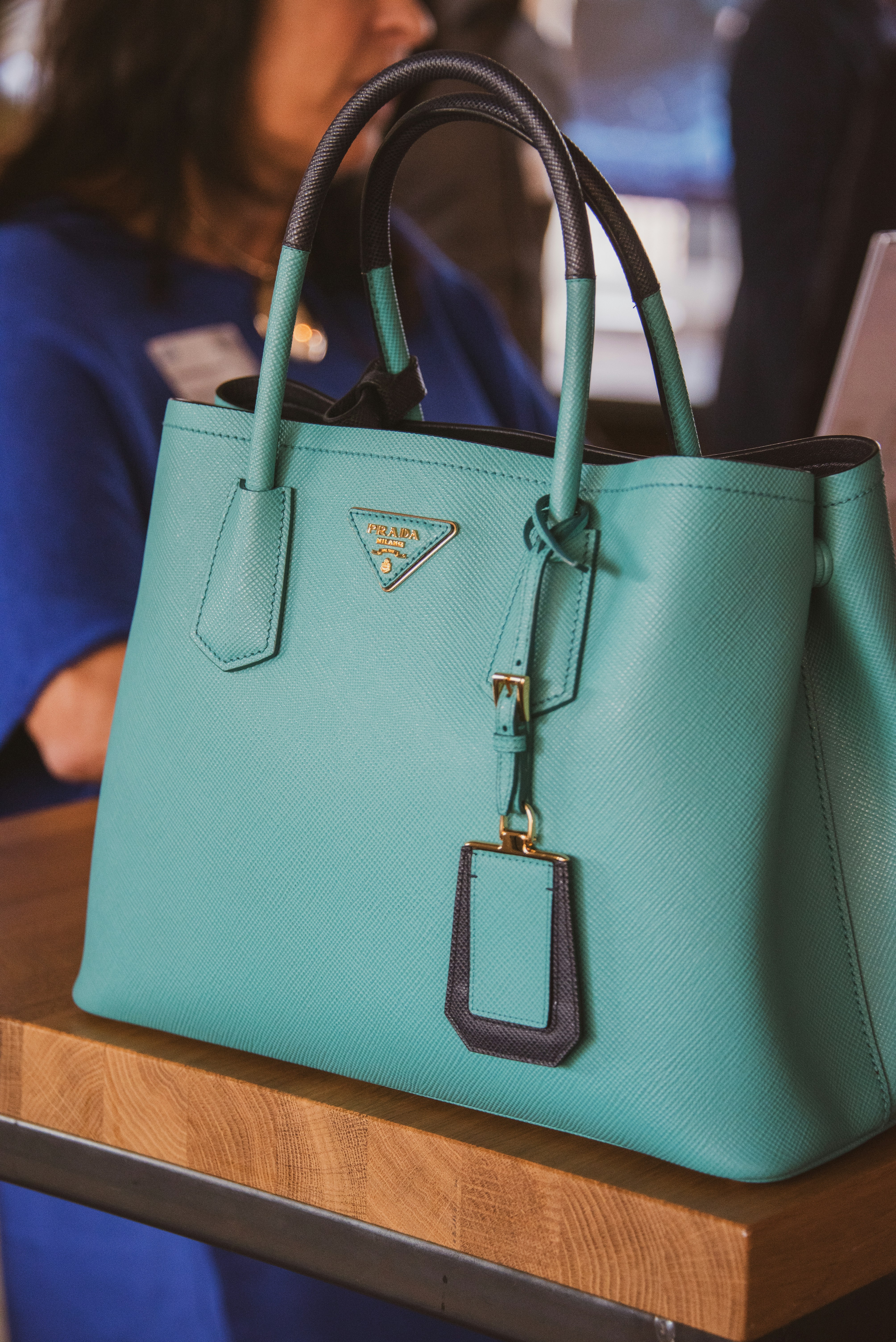 A woman sitting at a table with a blue purse