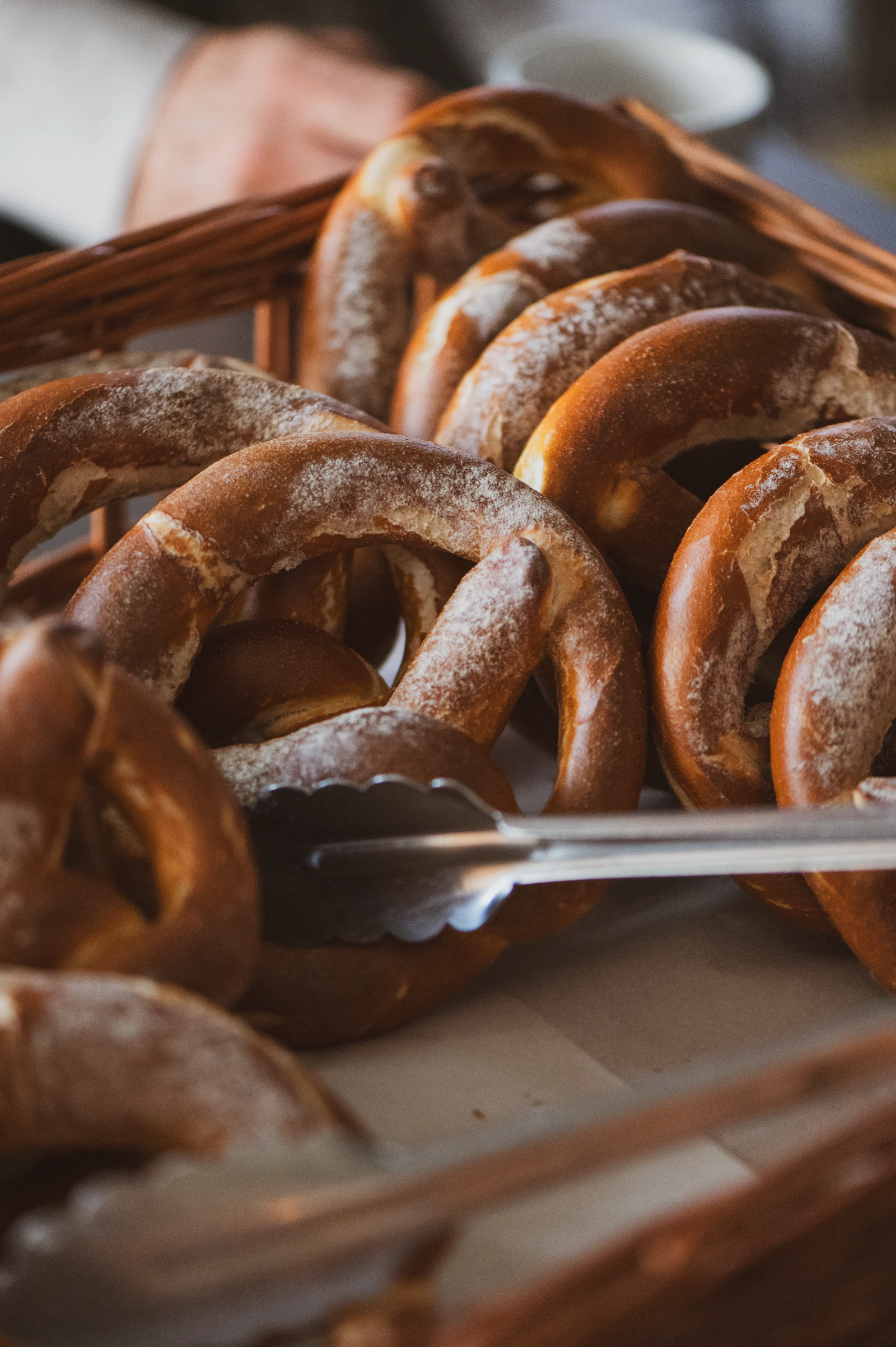 Salted pretzels fill a wooden basket on a table.