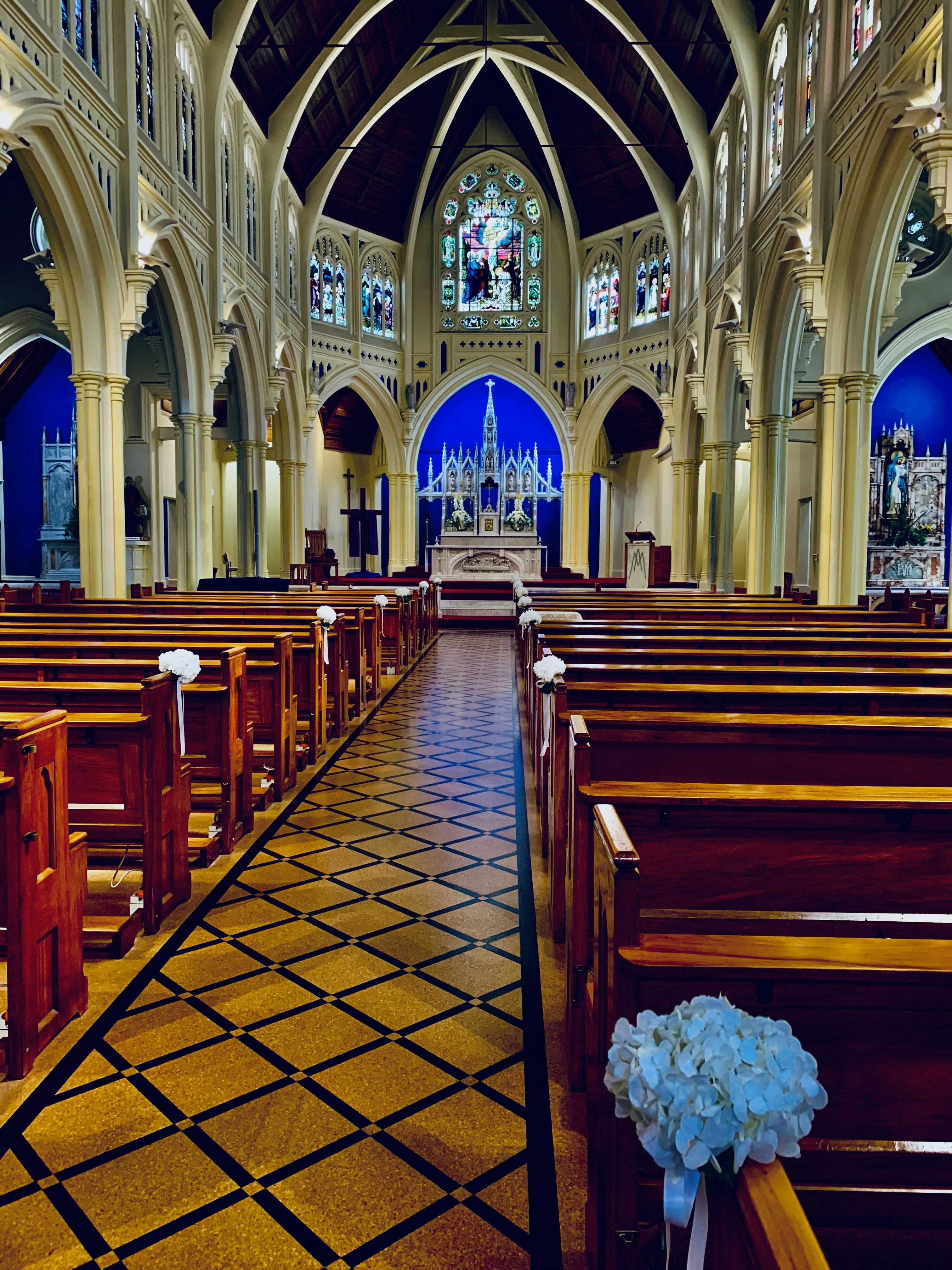 Church interior with stained glass windows casting colorful light patterns, empty wooden pews, quiet and peaceful atmosphere