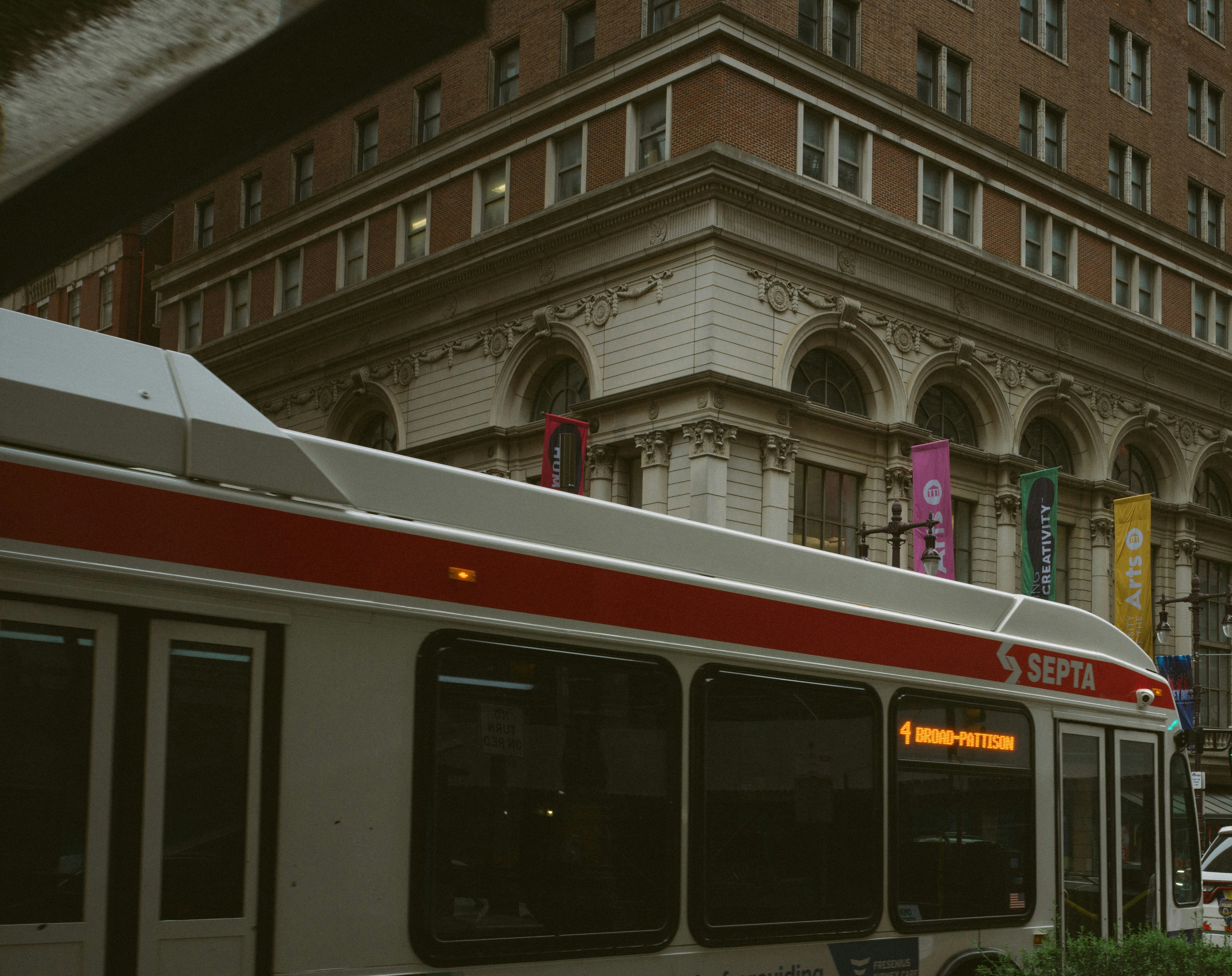 A city bus driving down a street next to tall buildings