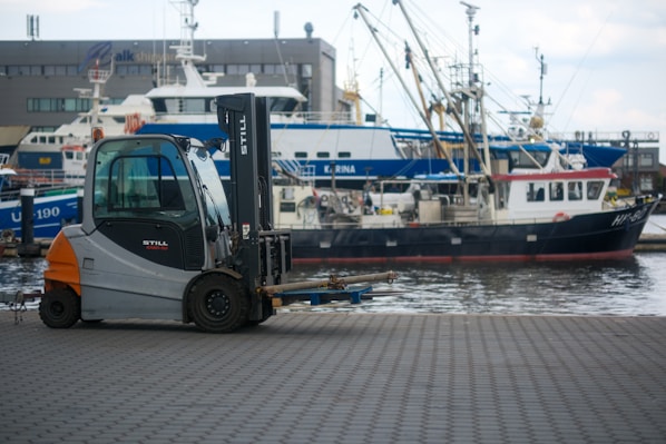 A forklift with a boat in the background