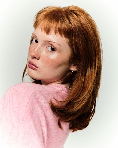 A woman with red hair is posing for a picture