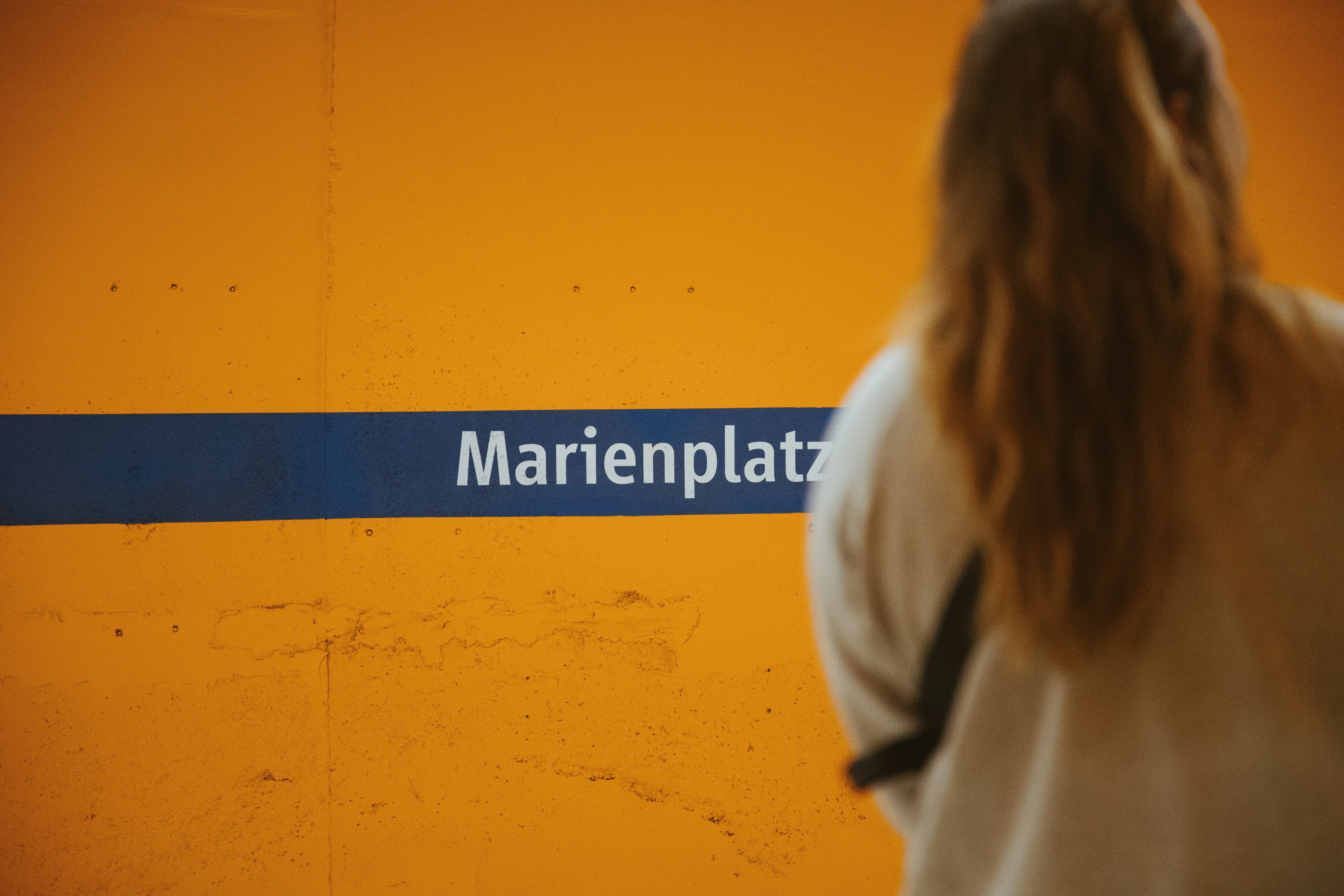 A woman walking past a train station sign
