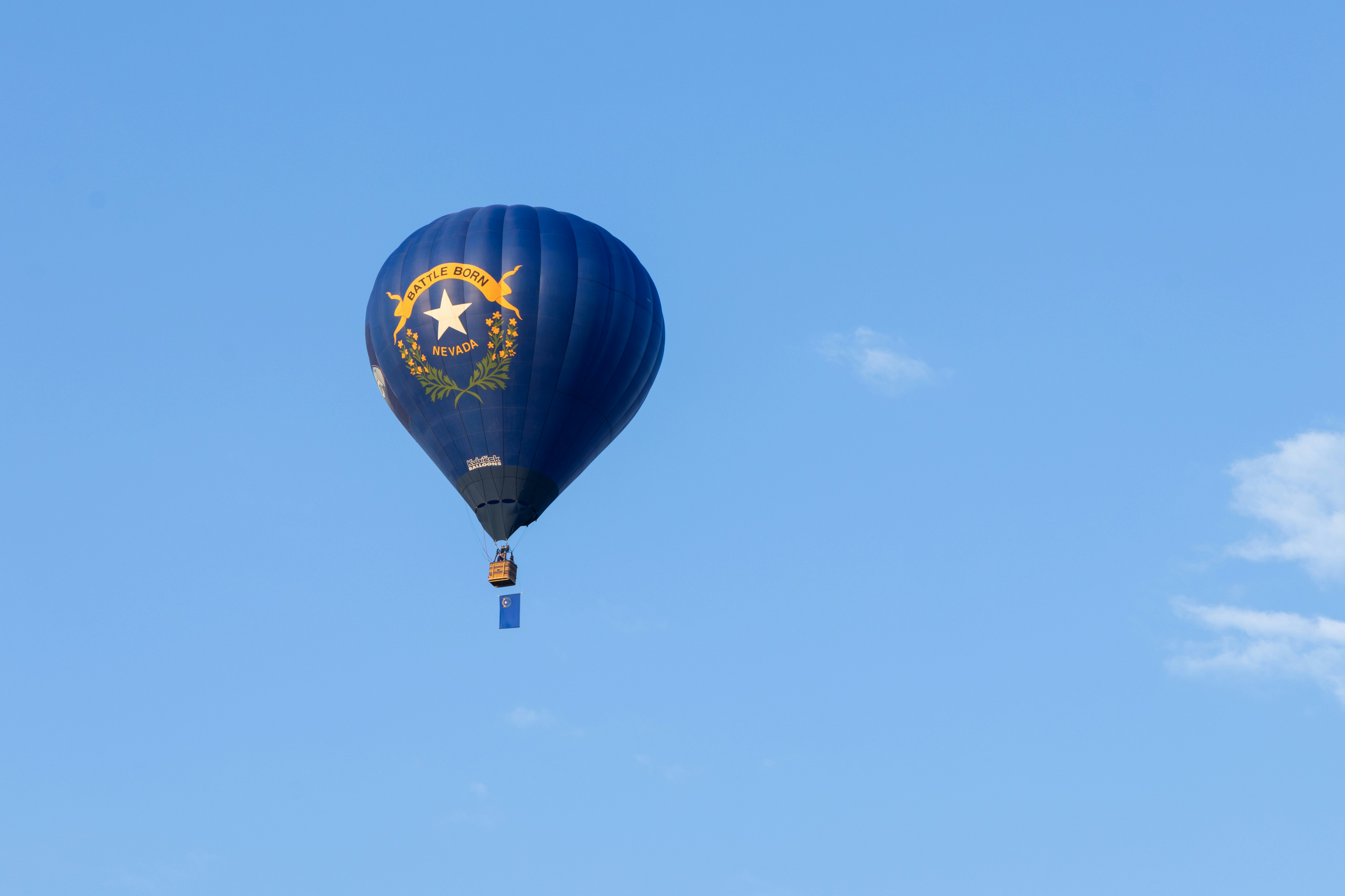 Blue hot air balloon flying through blue sky