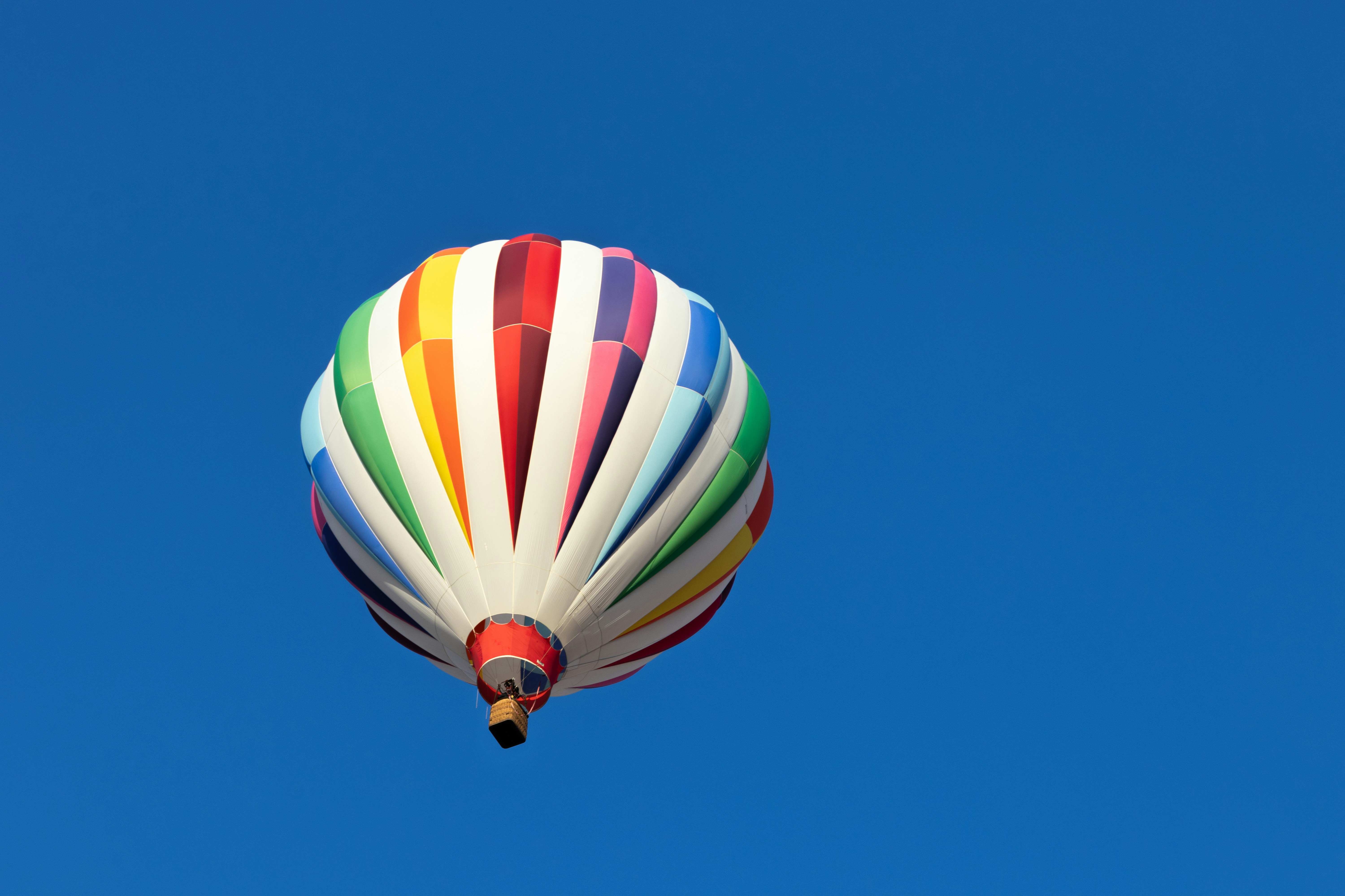 Colorful hot air balloon flying through blue sky