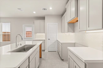 A kitchen with a sink, stove, cabinets and a refrigerator