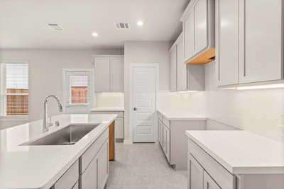 A kitchen with a sink, stove, cabinets and a refrigerator