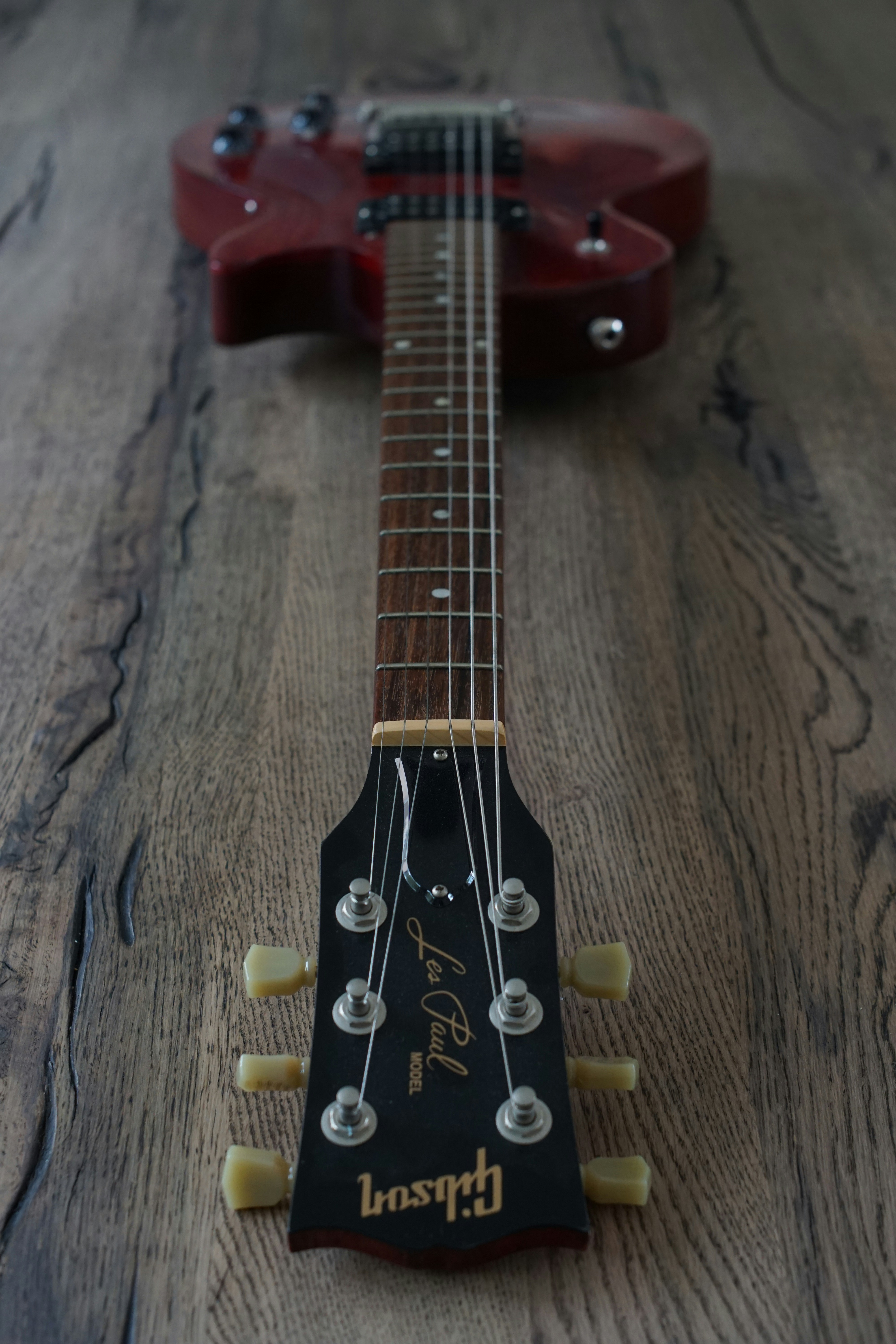 A red guitar sitting on top of a wooden floor
