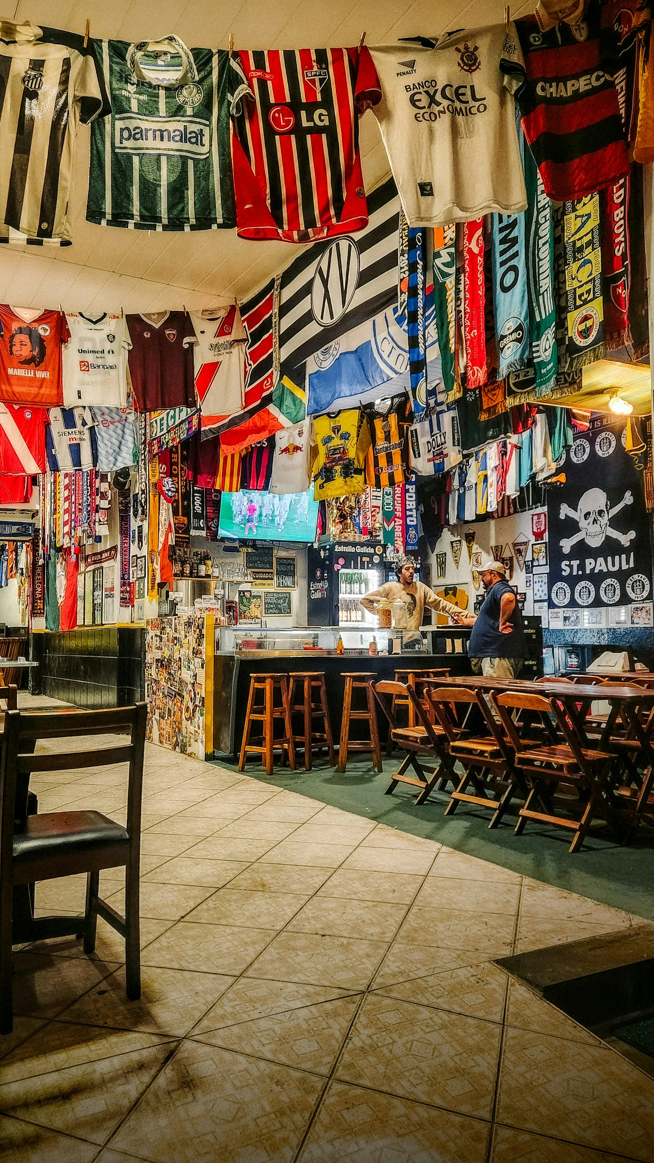 Sports bar interior with large screens showing football, dimly lit atmosphere, crowd watching intently