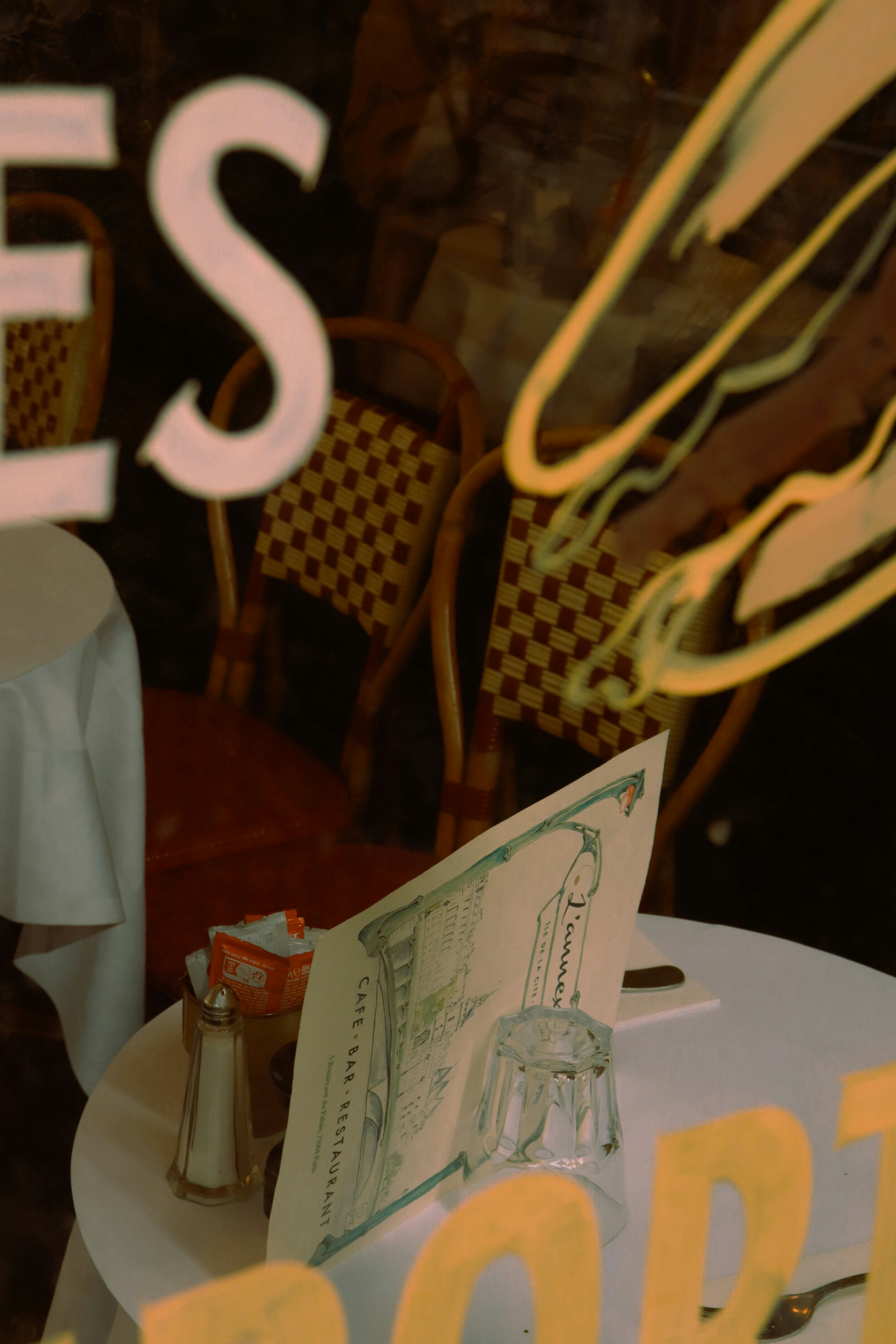 A restaurant window with a table and chairs in front of it