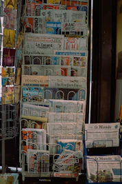 A stack of newspapers sitting on top of a blue cart