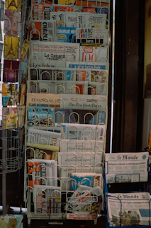 A stack of newspapers sitting on top of a blue cart