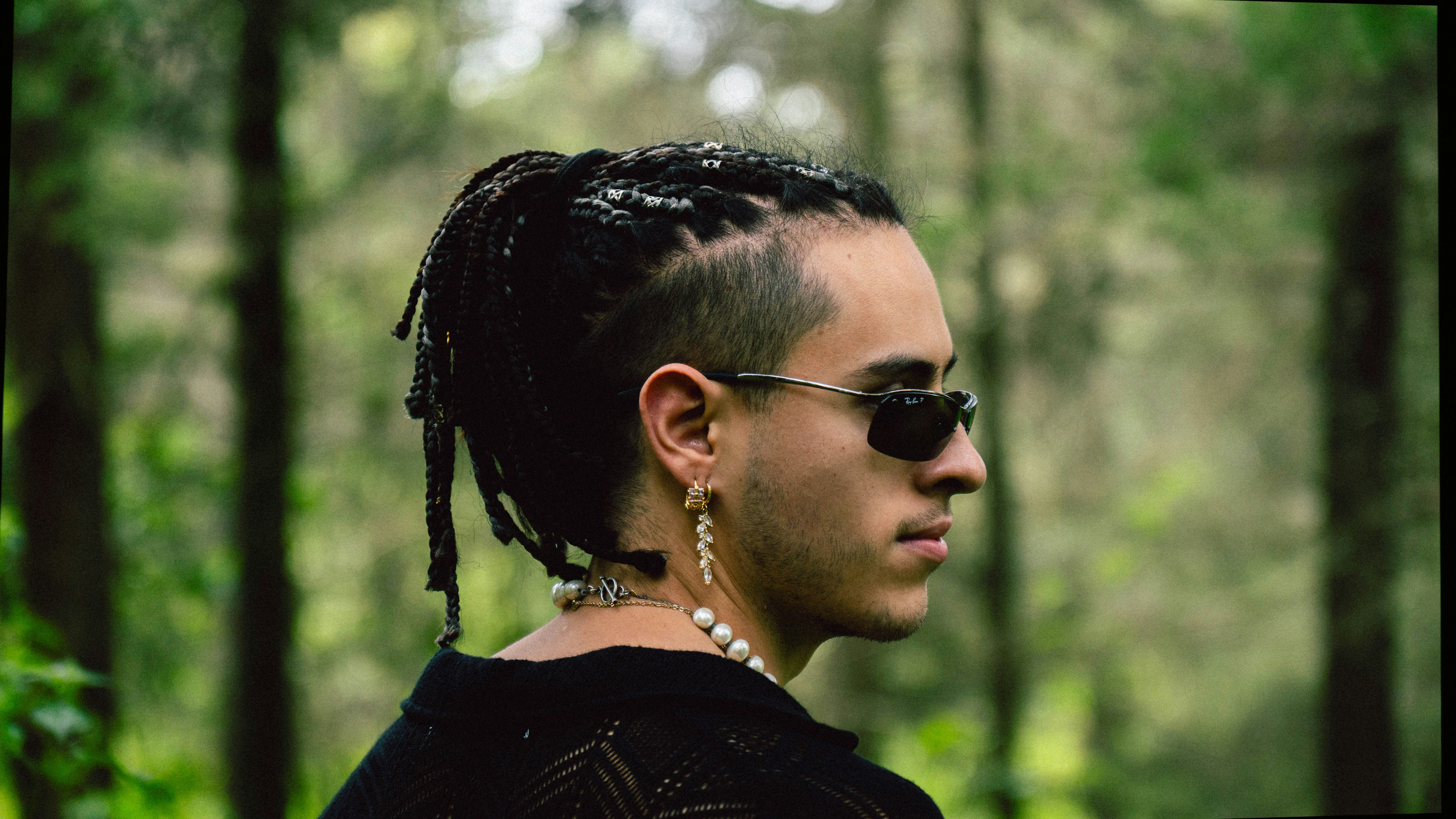 Un hombre con rastas parado en el bosque