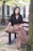 A woman sitting on top of a wooden bench