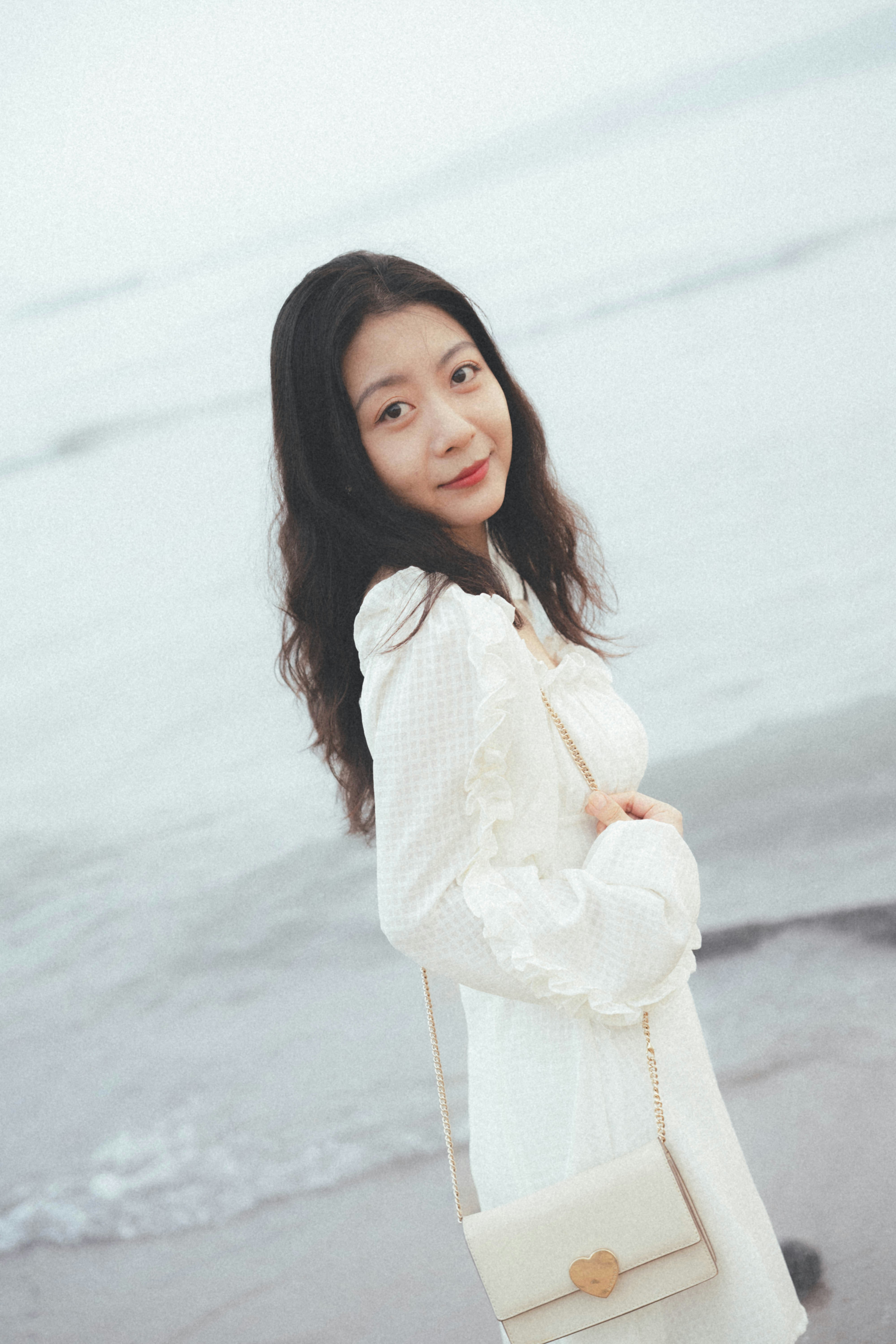 A woman standing on a beach next to the ocean