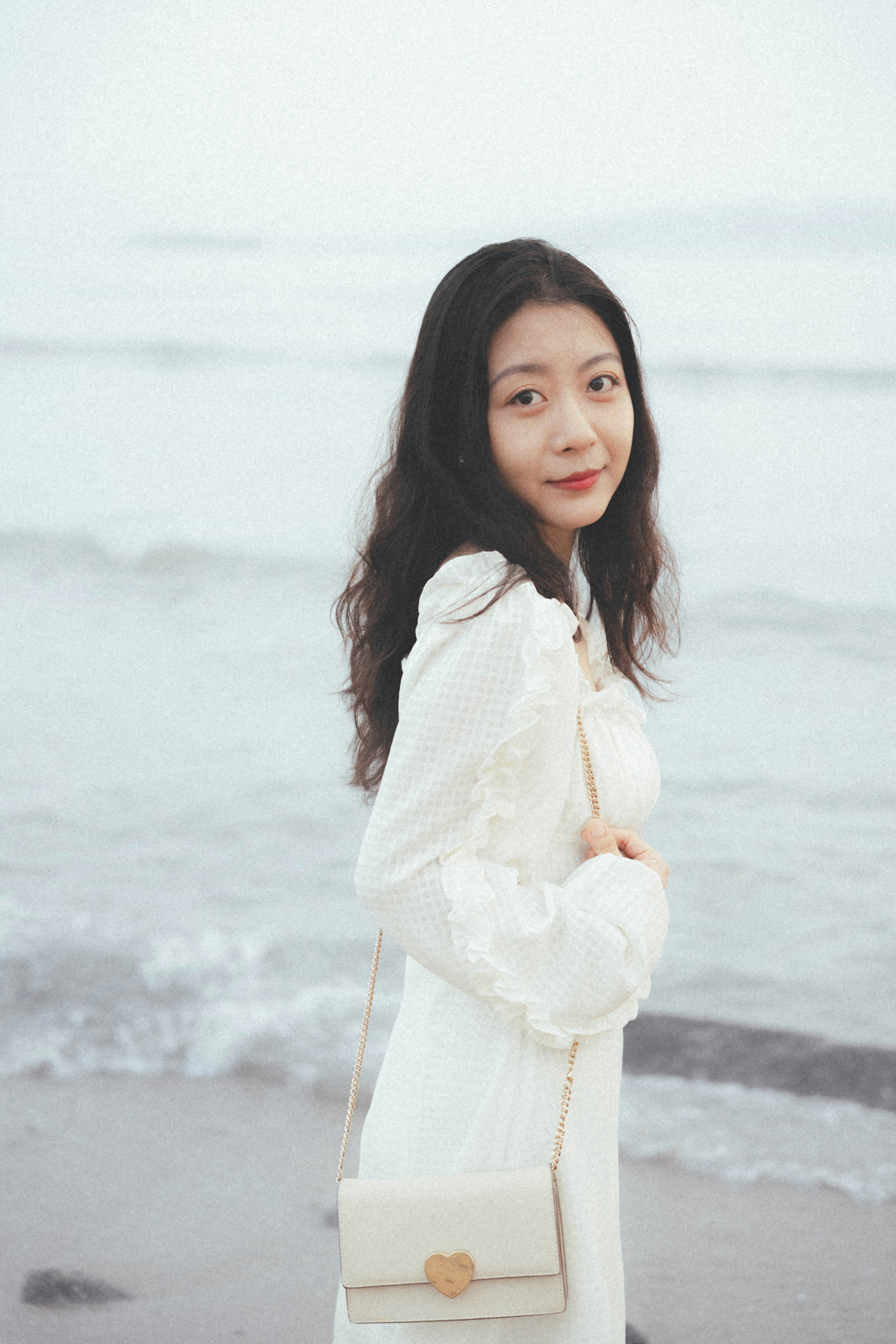 A woman standing on a beach next to the ocean