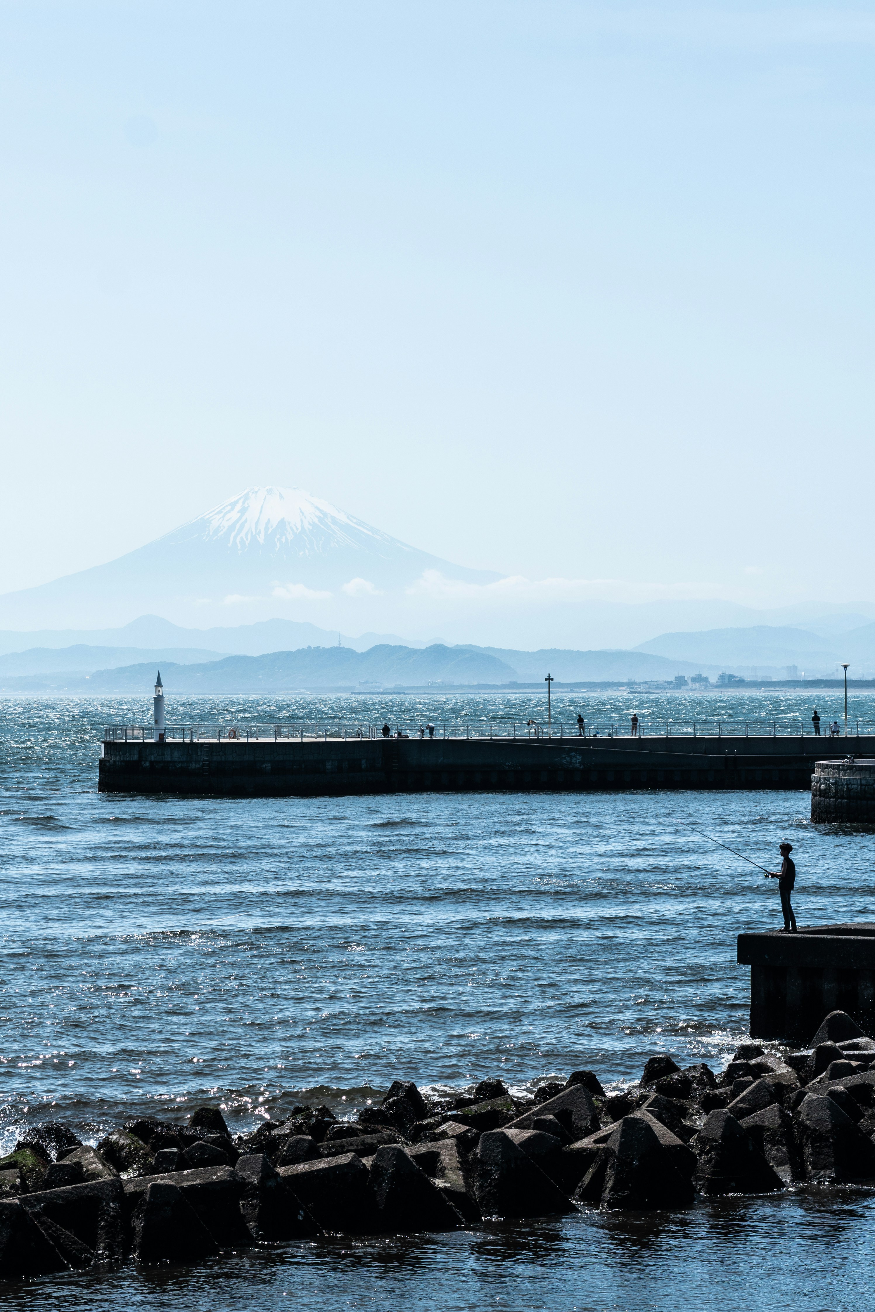 Un hombre de pie en un muelle junto a un cuerpo de agua