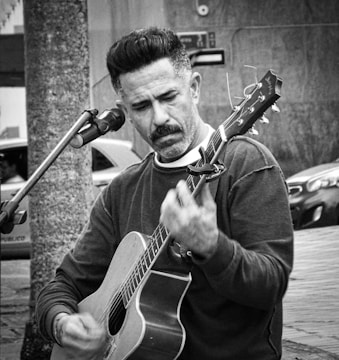 A man holding a guitar while standing in front of a microphone