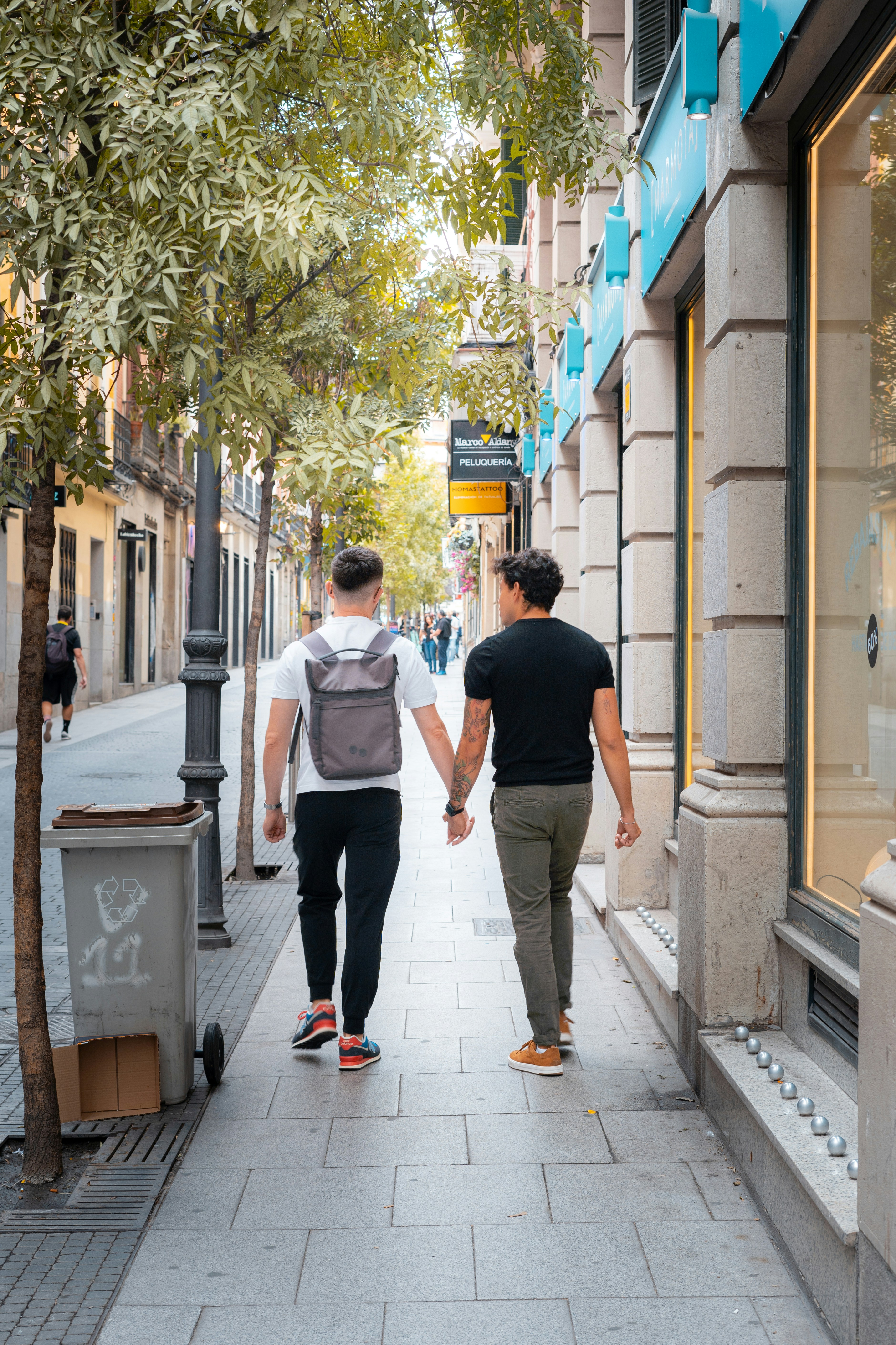 Two people walking down a sidewalk holding hands