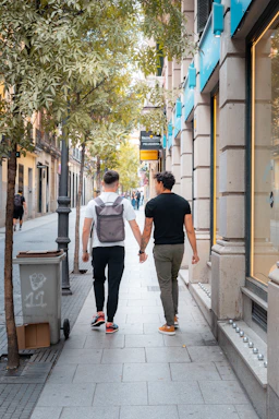 Two people walking down a sidewalk holding hands