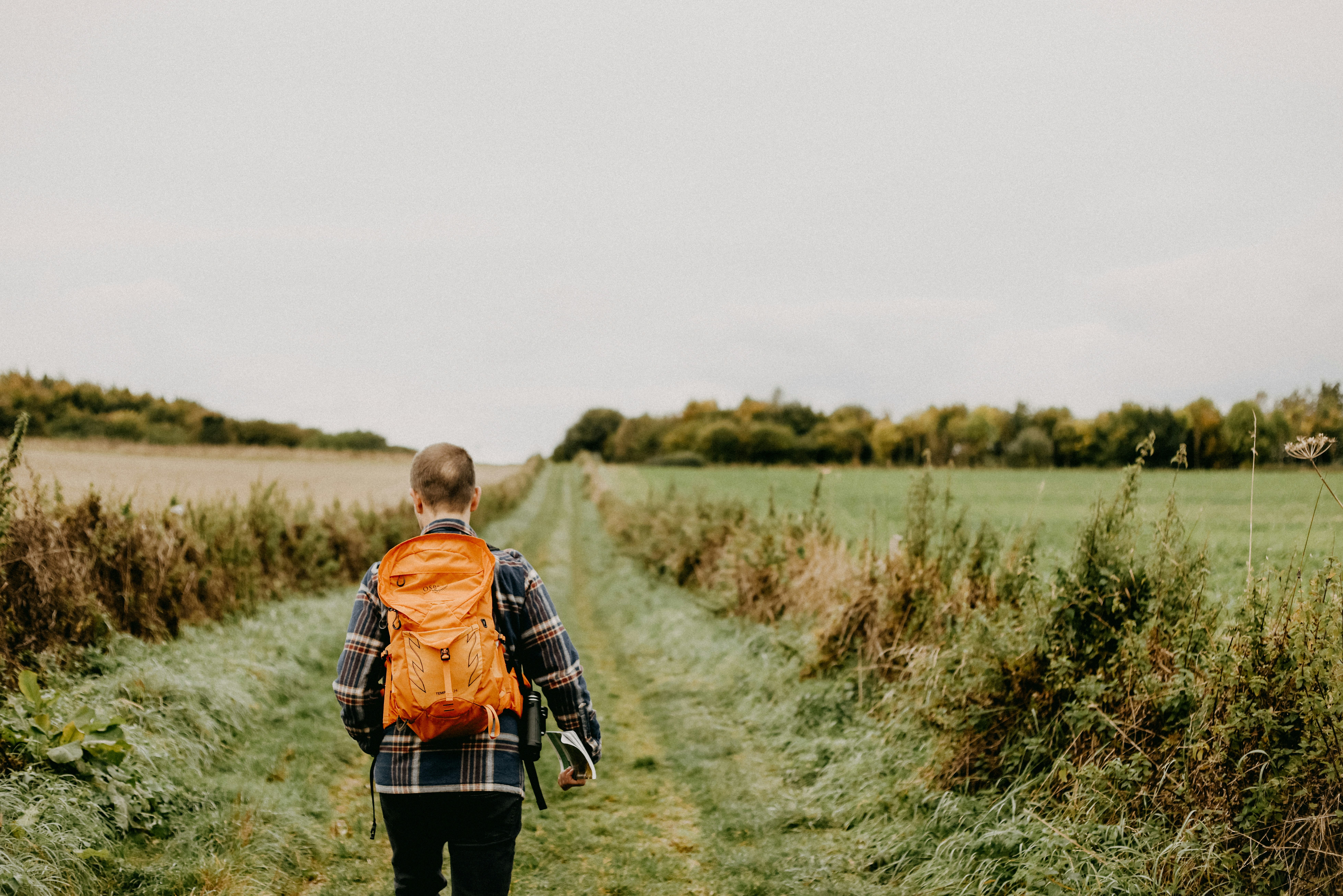 A person with a backpack walking down a dirt road