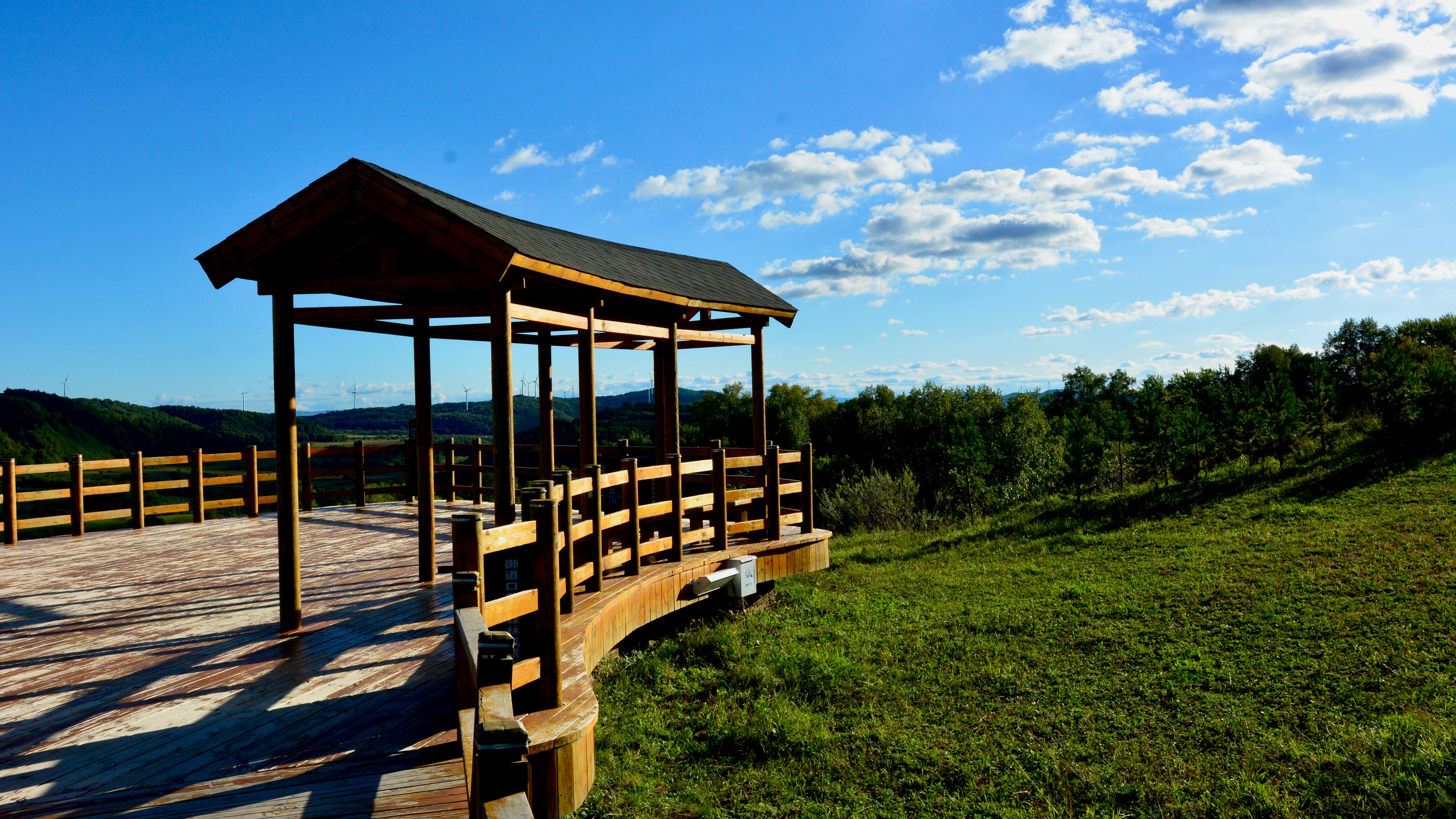 A wooden gazebo sitting on top of a lush green field