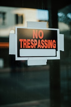 A no trespassing sign hanging on a window