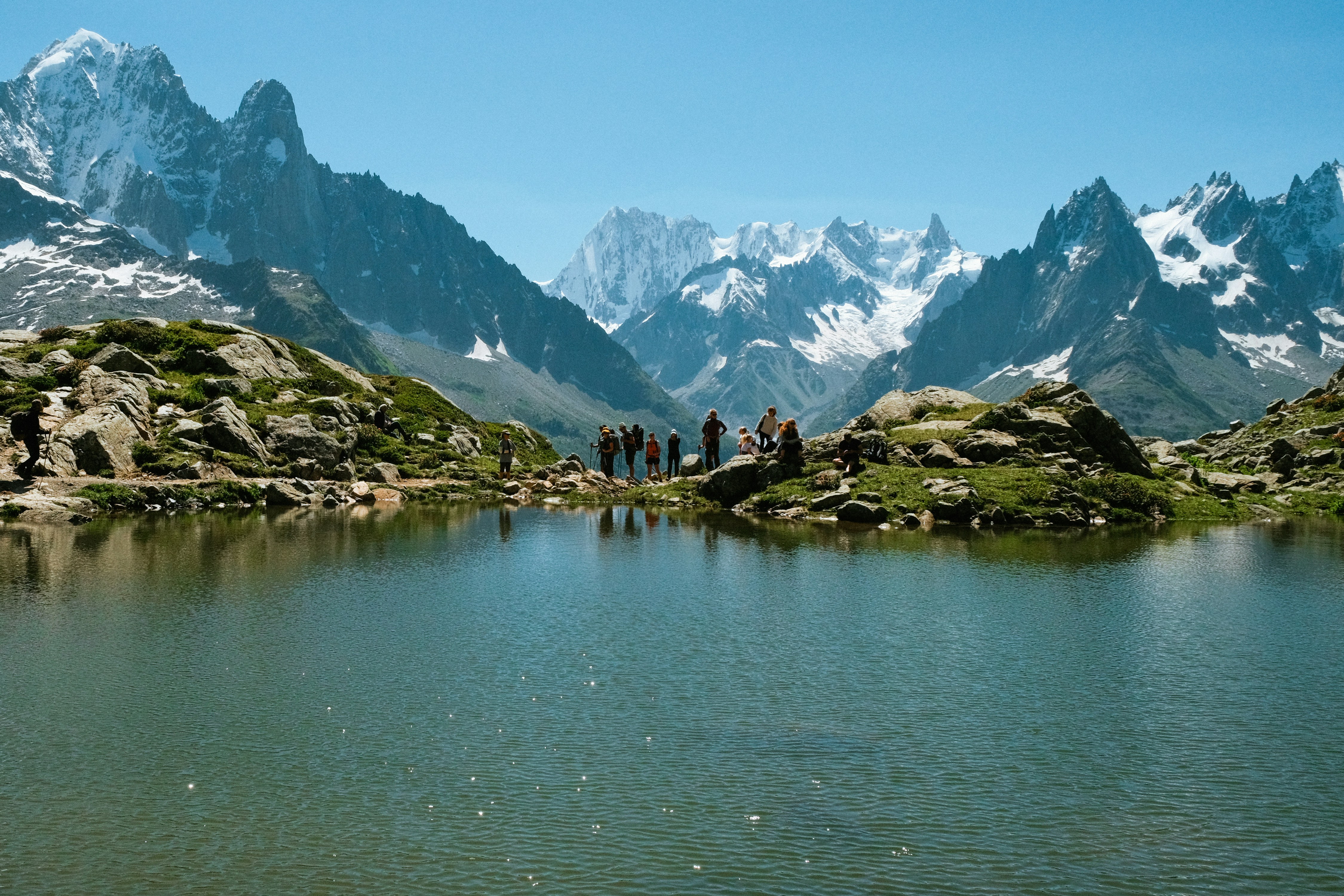 Un groupe de personnes debout au sommet d’une montagne à côté d’un lac