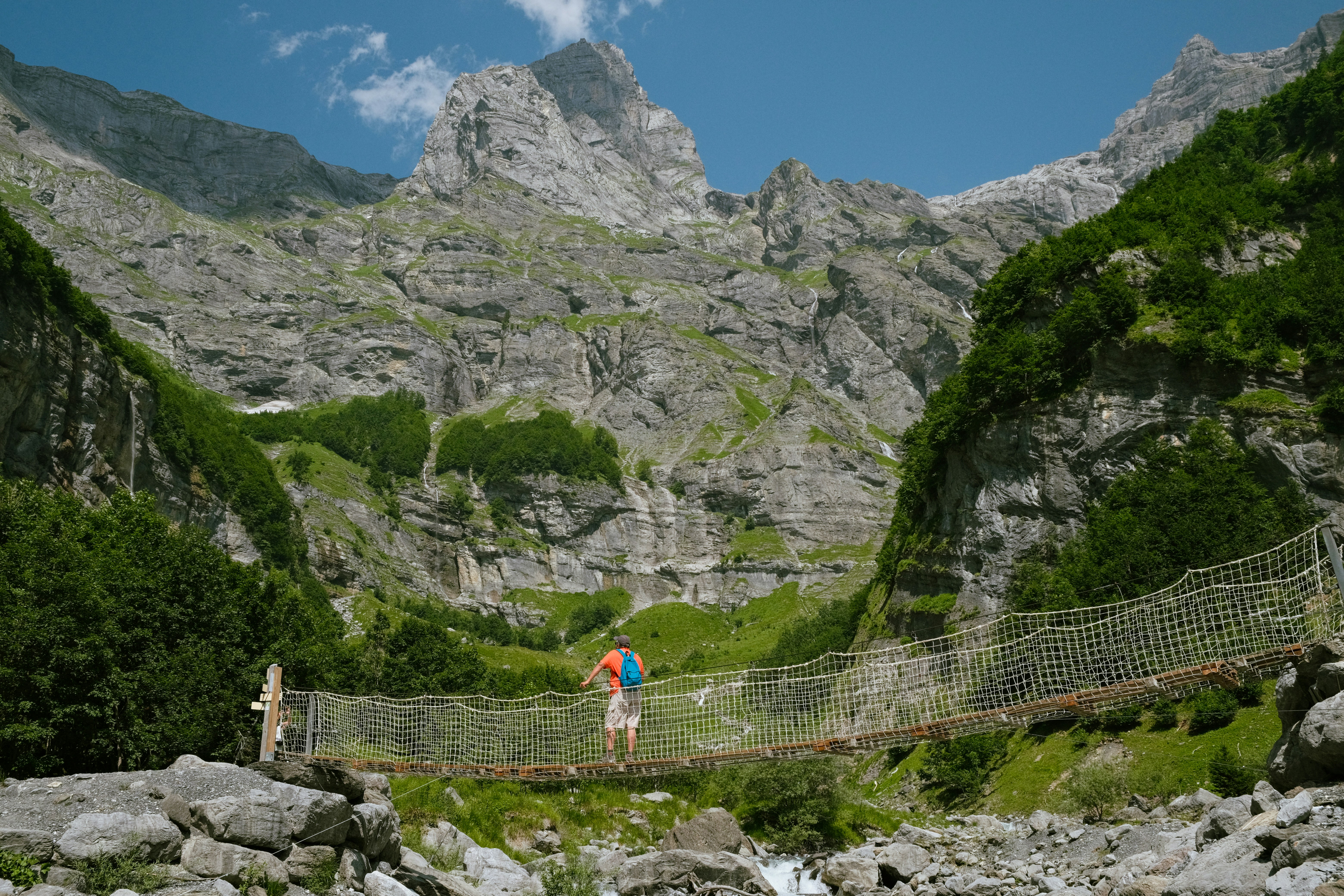 Two people crossing a suspension bridge in the mountains