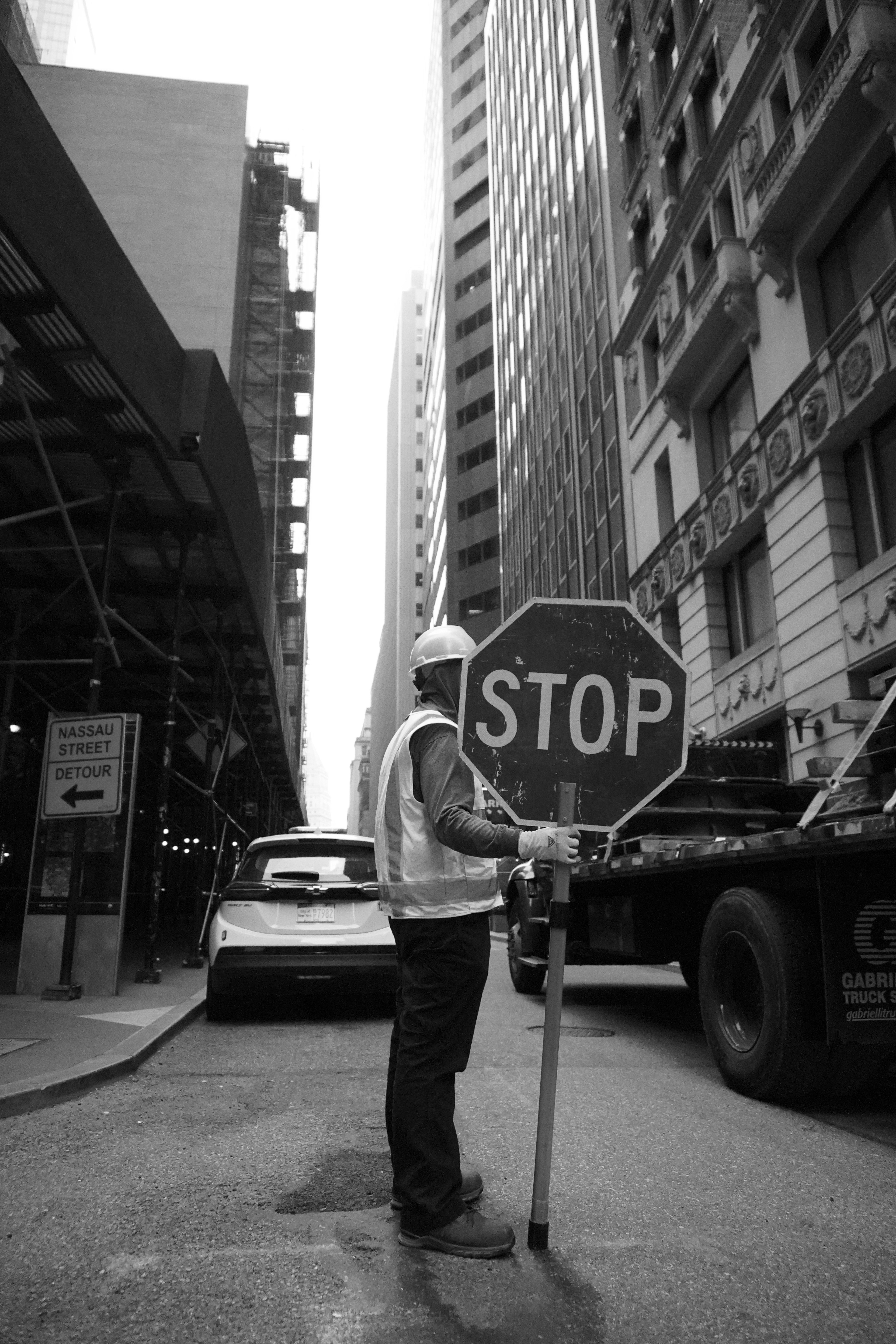 Un uomo, in piedi accanto a un segnale di stop su una strada della città