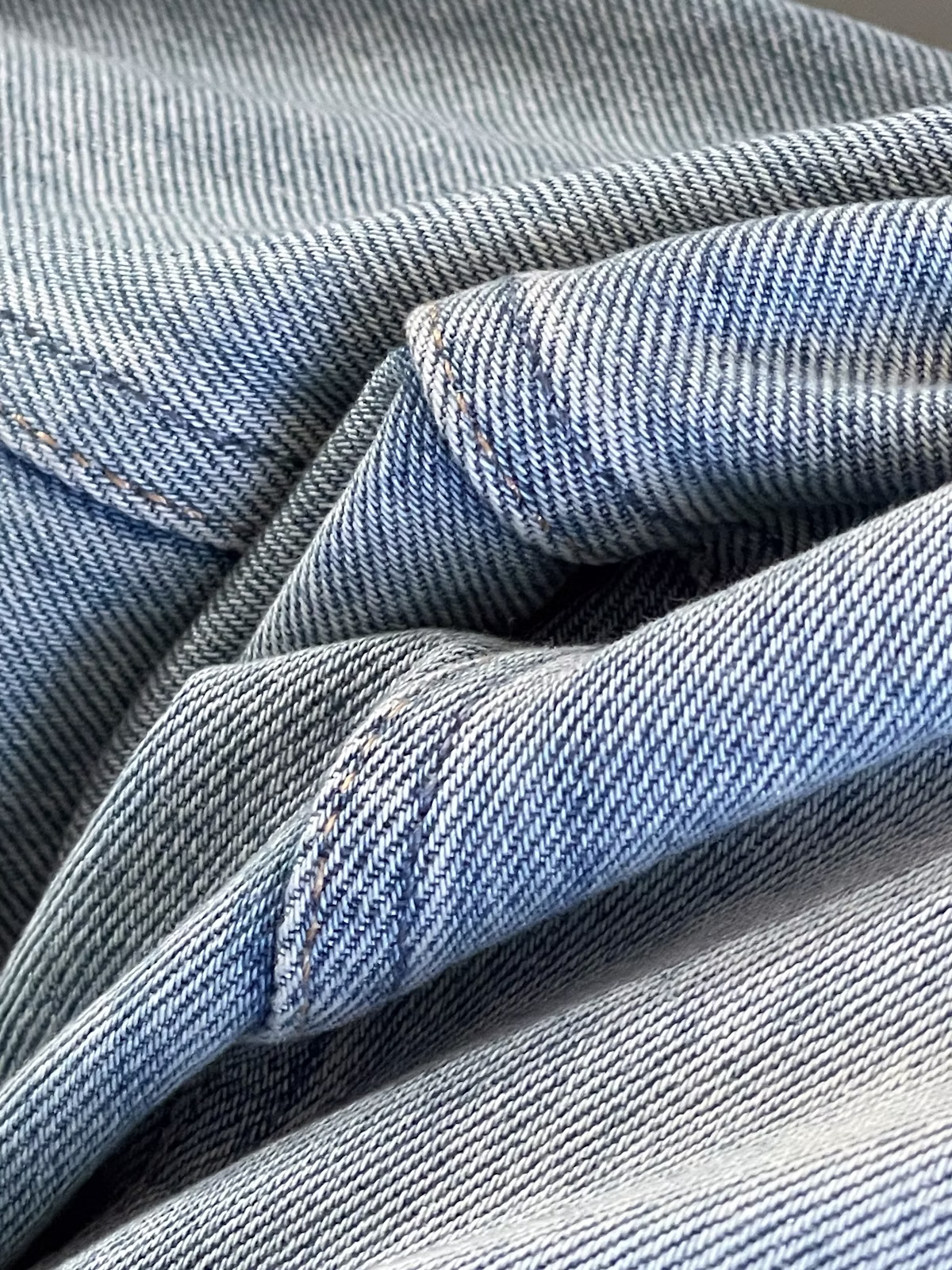 Close-up of blue jeans being altered with needle and thread