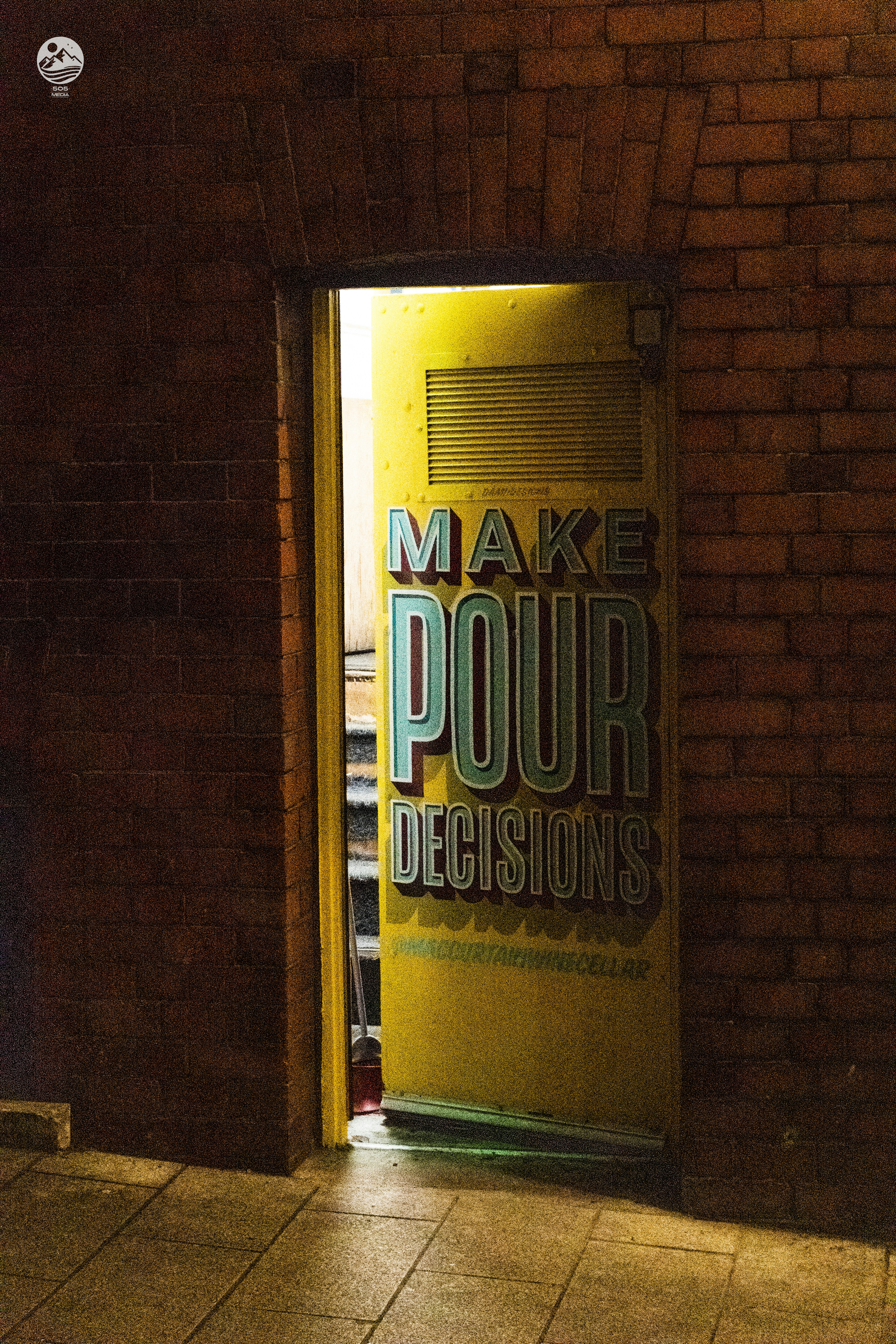 A yellow door is open on a brick building