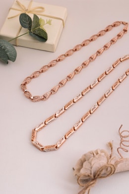 A rose gold necklace on a white table
