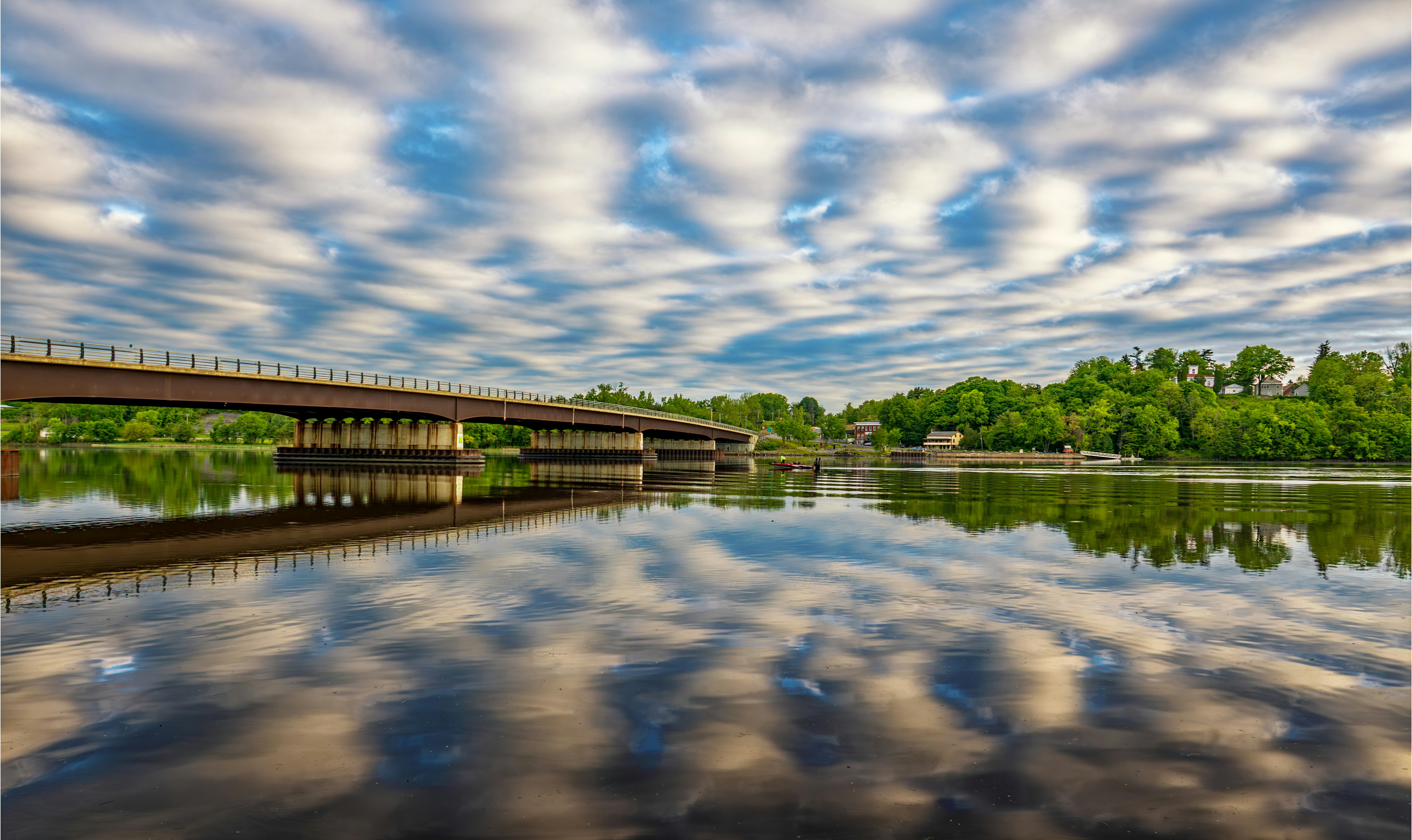 A long bridge over a river under a cloudy sky