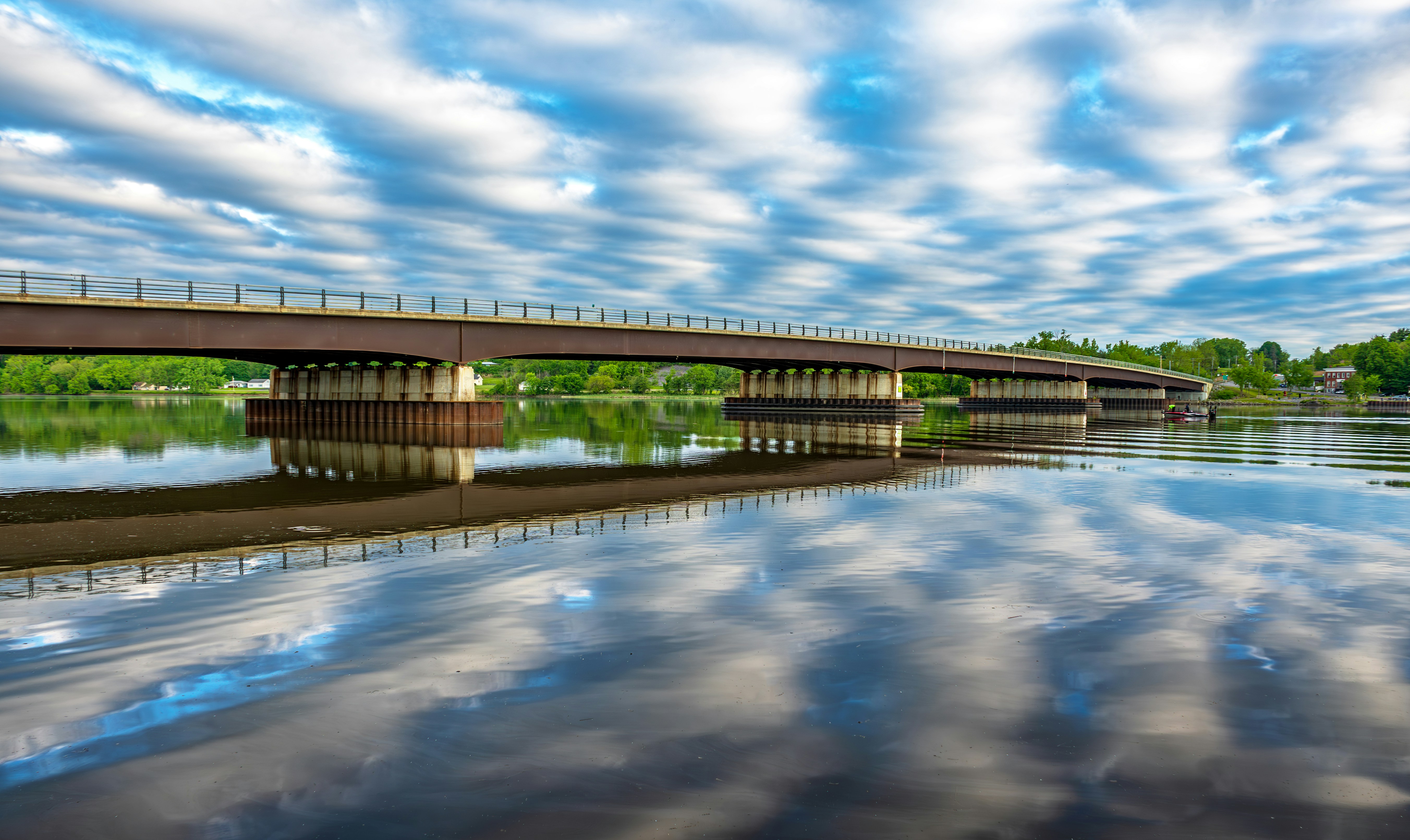 A long bridge over a river under a cloudy sky