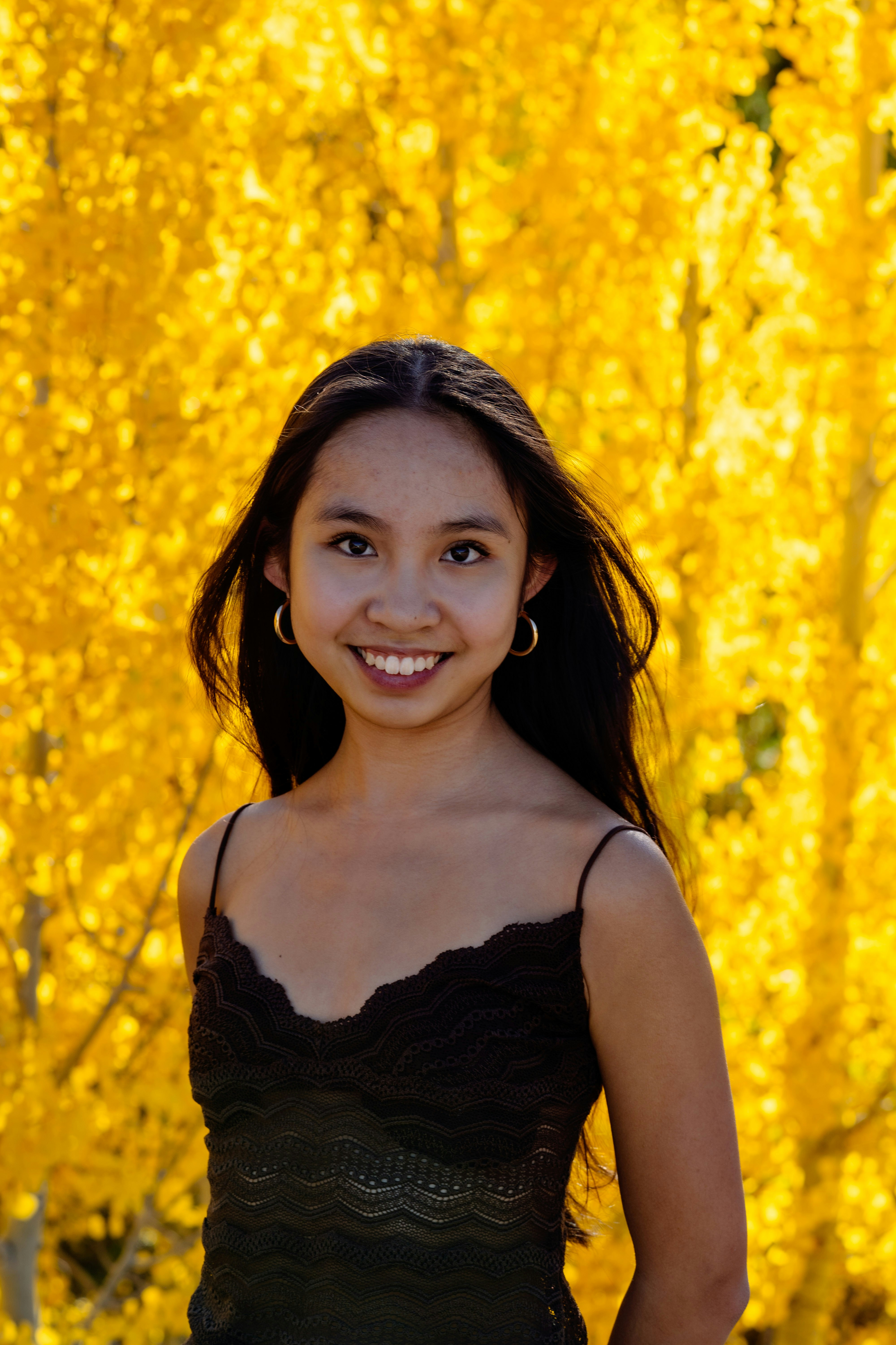 A young girl standing in front of a yellow tree
