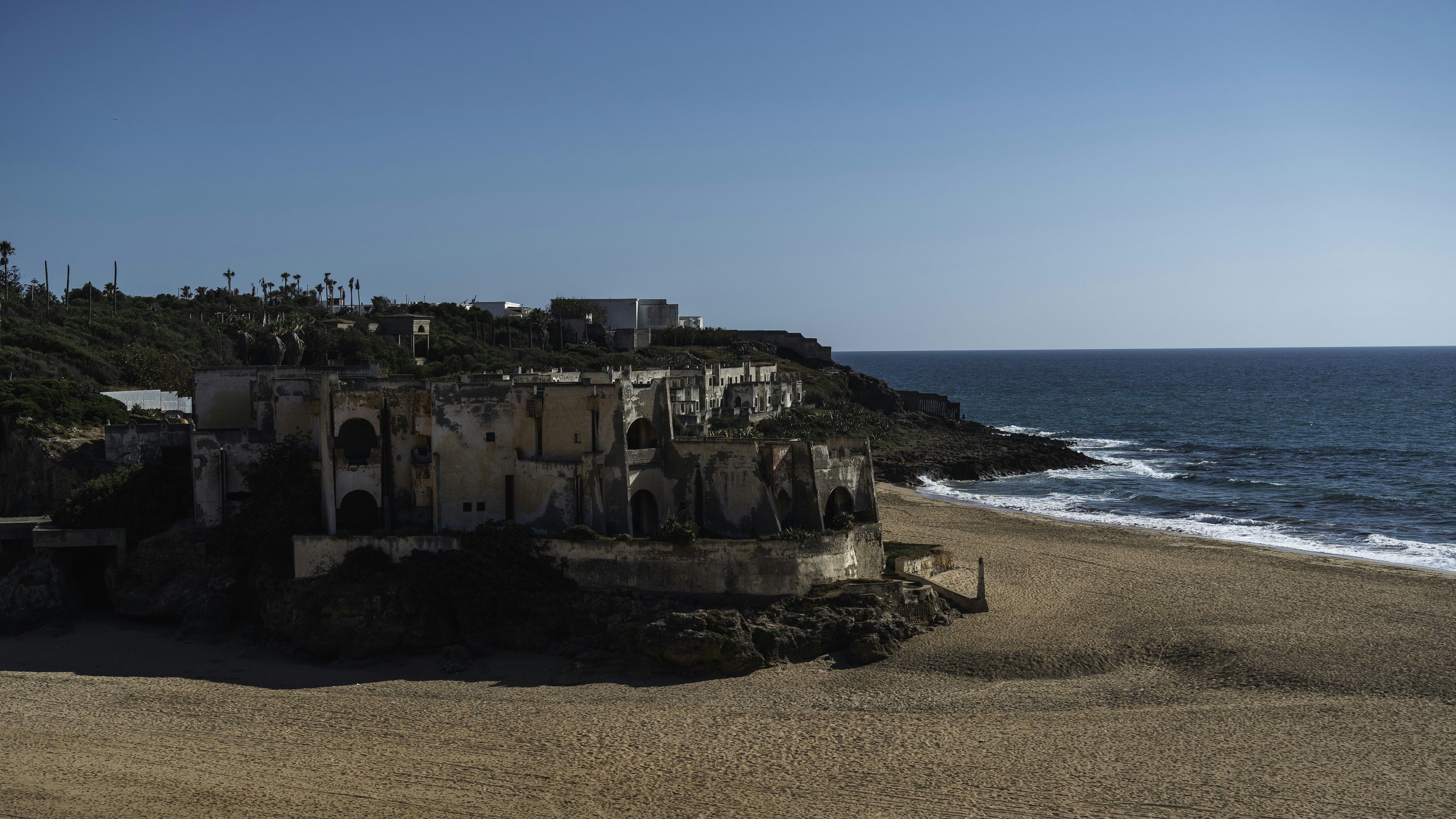 A sandy beach next to the ocean under a blue sky