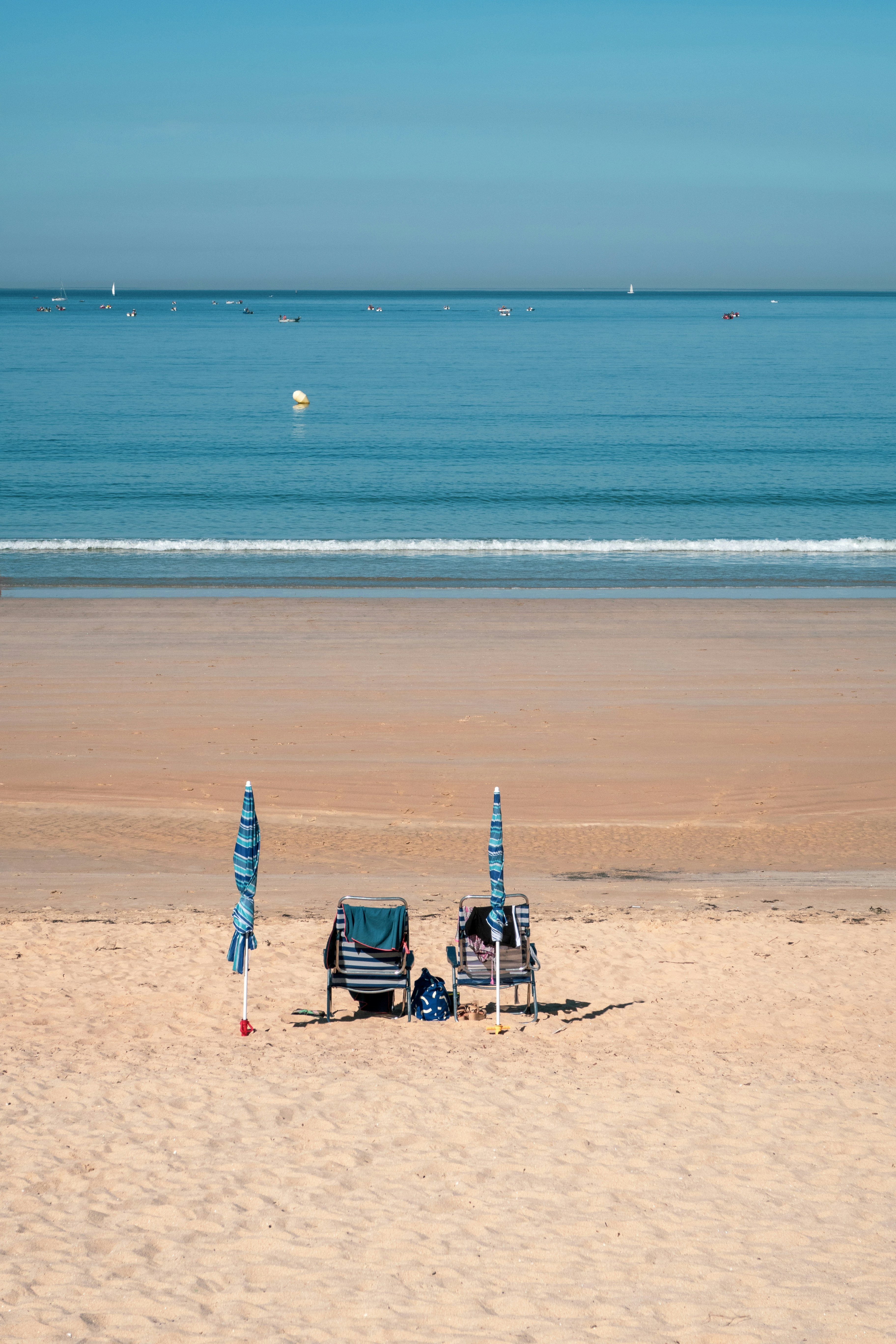 Un par de sillas de jardín sentadas en la parte superior de una playa de arena