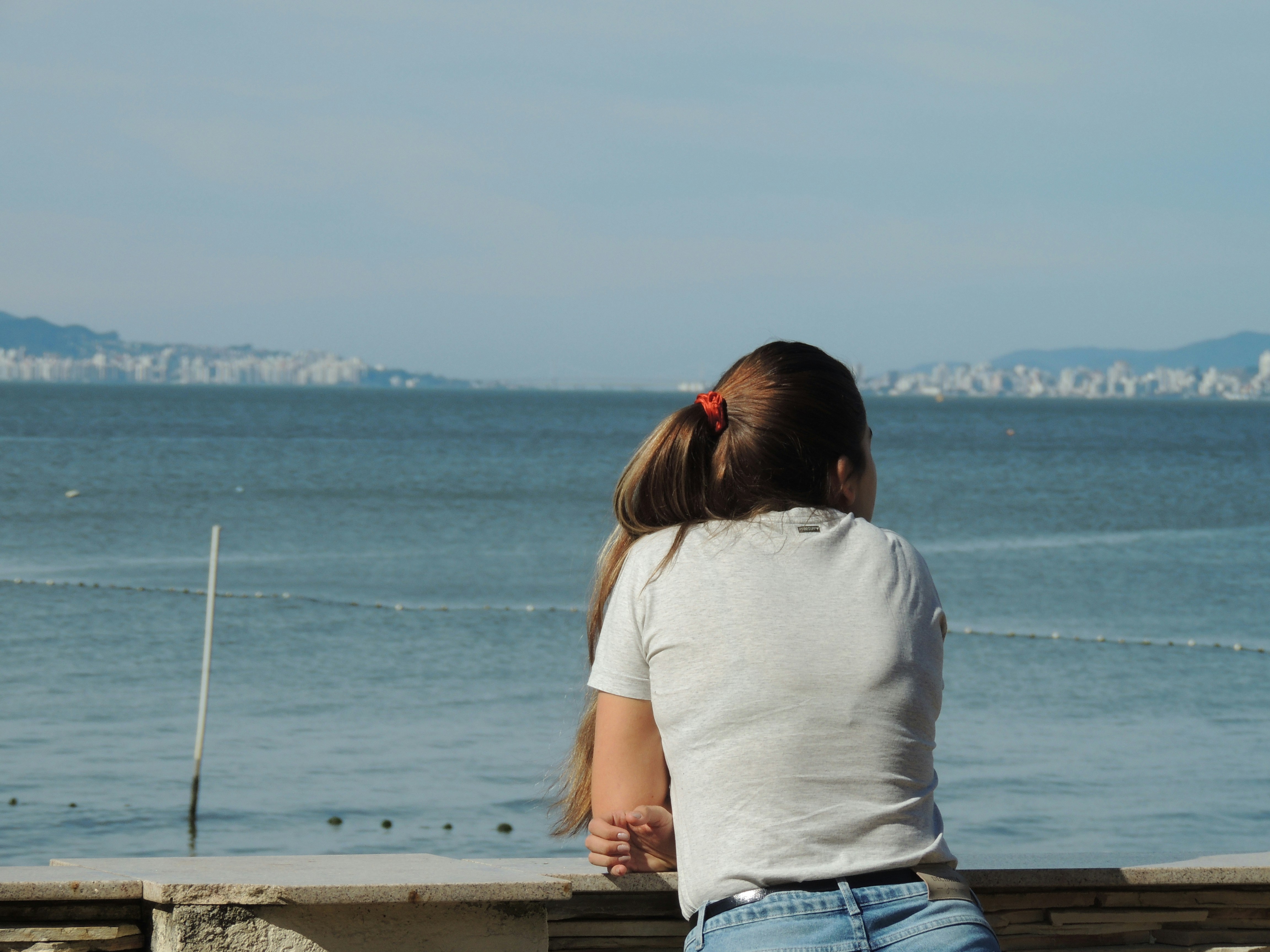A woman sitting on a bench looking out at the ocean