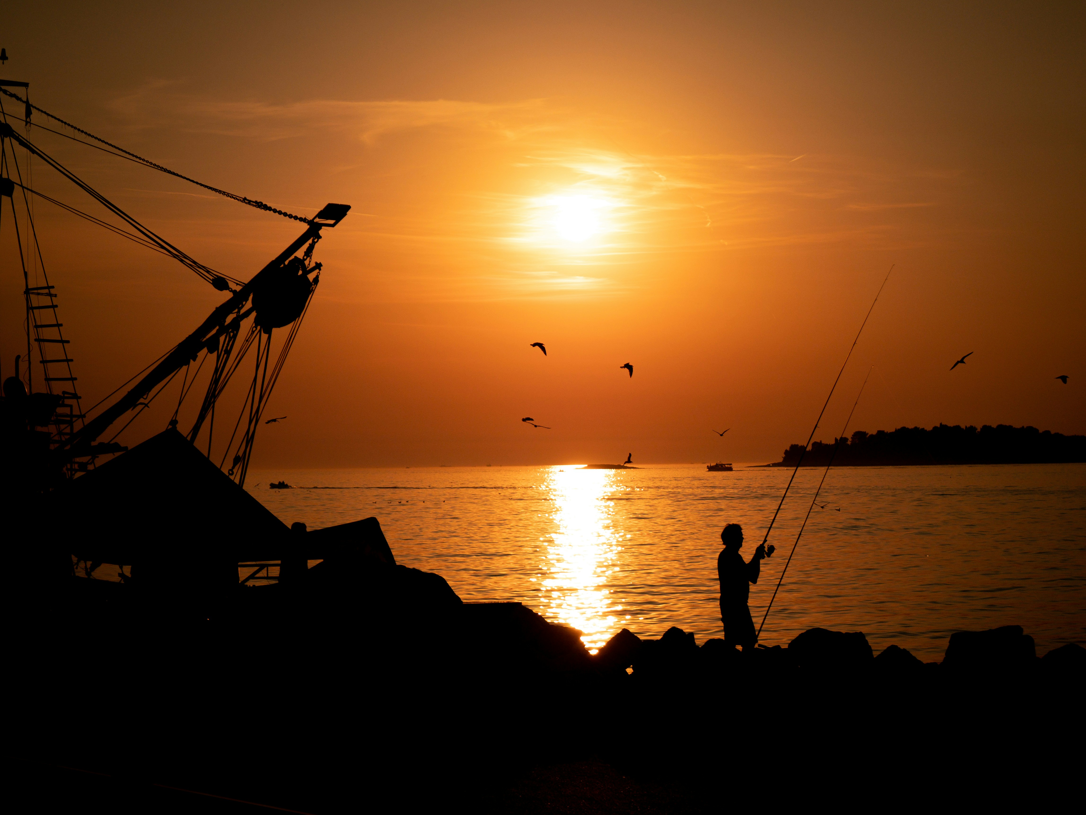 A person fishing at sunset on the beach