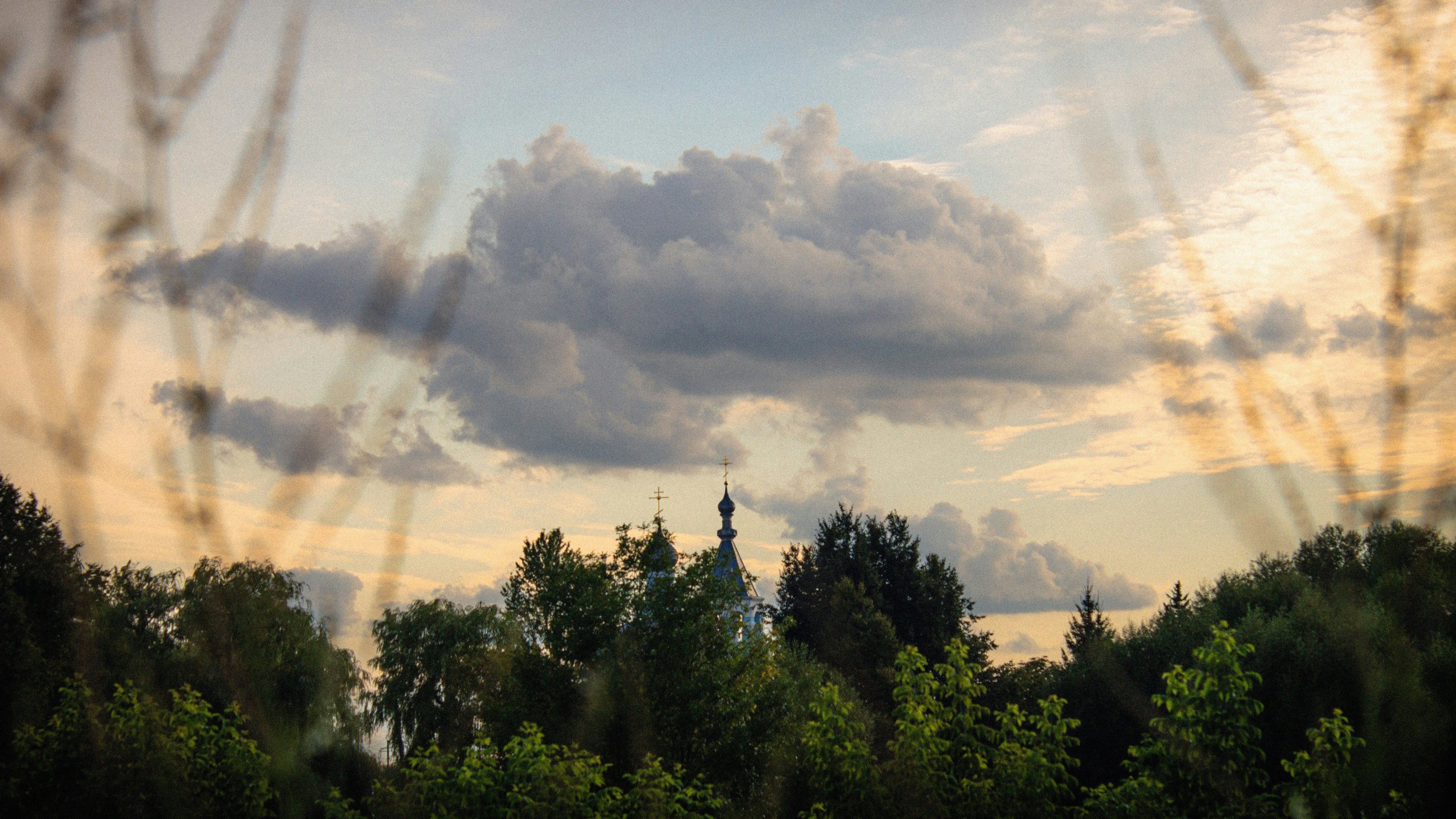 A picture of a cloudy sky with trees in the foreground