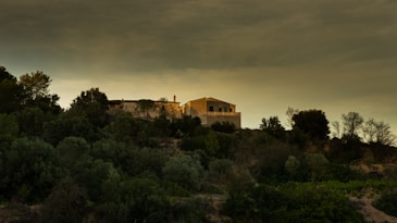 A house sitting on top of a hill under a cloudy sky