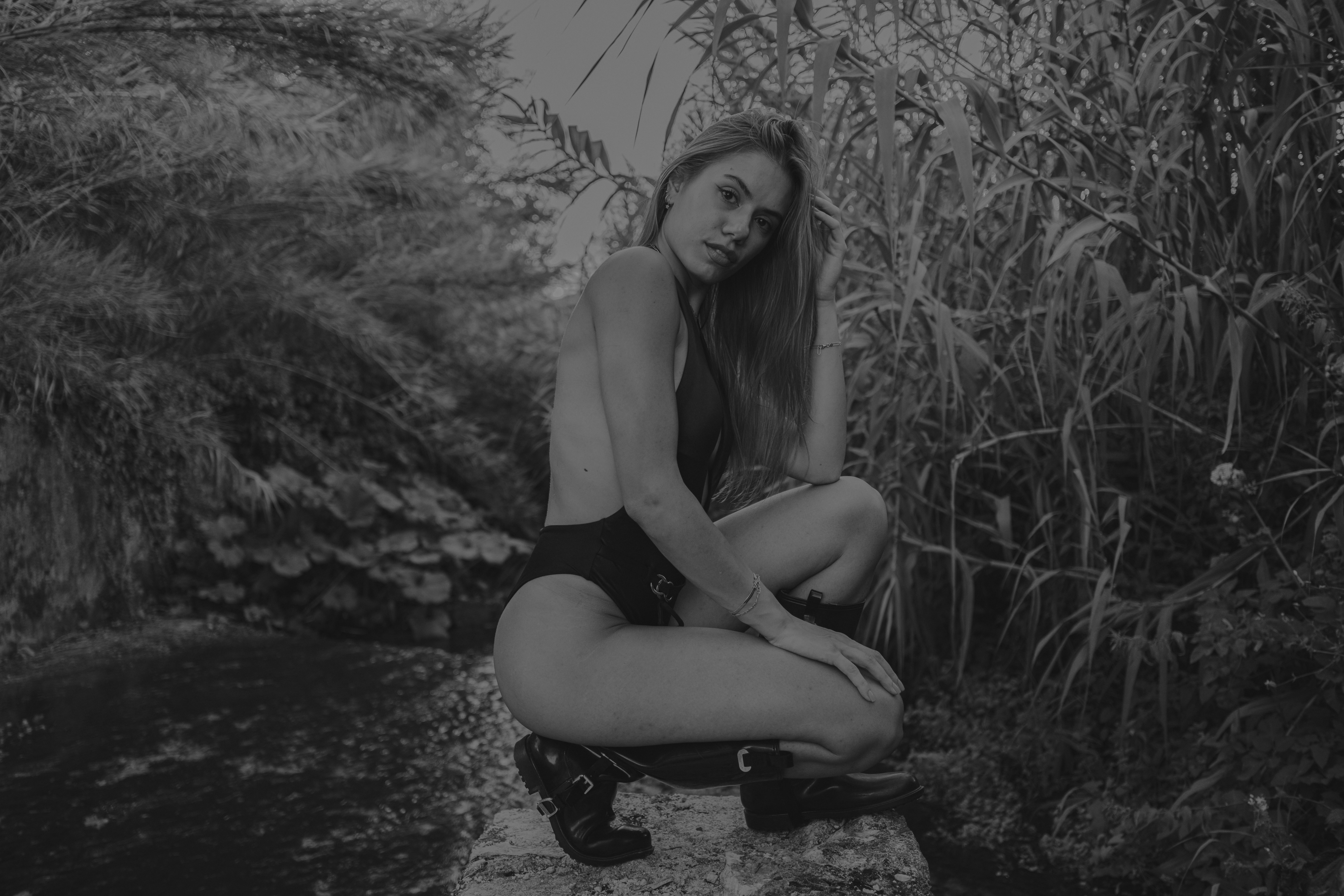 A woman sitting on a rock next to a body of water