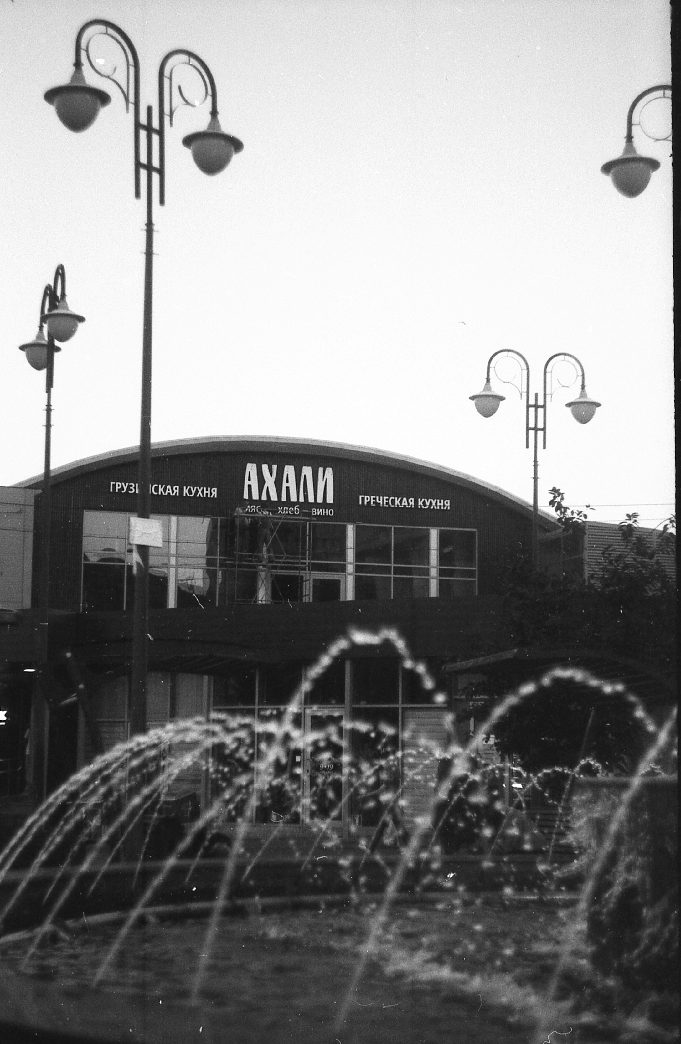 A black and white photo of a fountain in front of a building