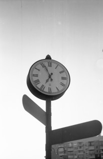 A black and white photo of a clock on a pole