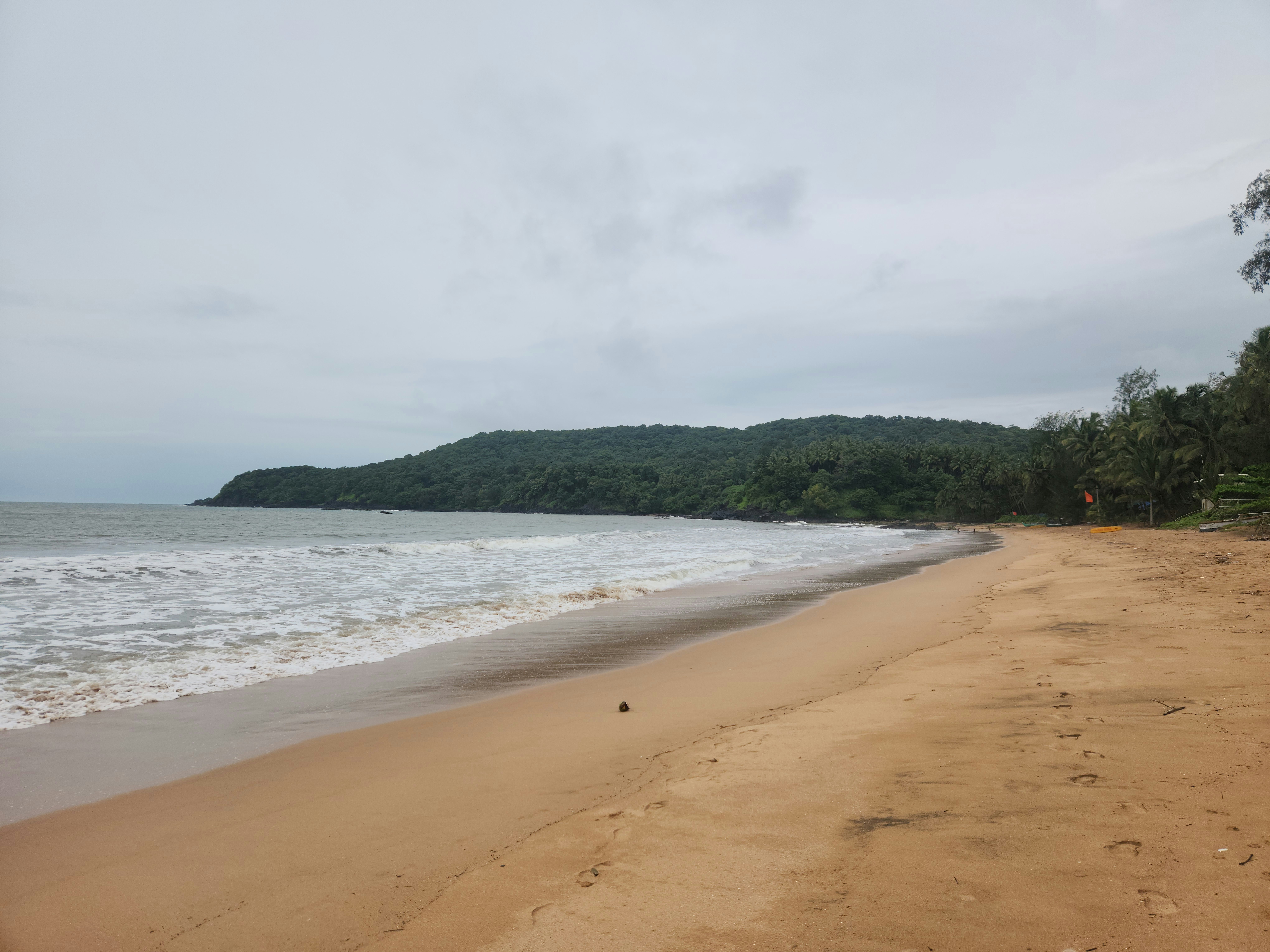 A sandy beach next to the ocean under a cloudy sky